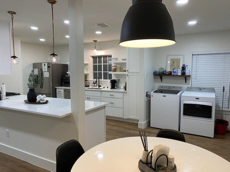 Modern open-concept kitchen with white cabinetry, a large island, and laundry area.