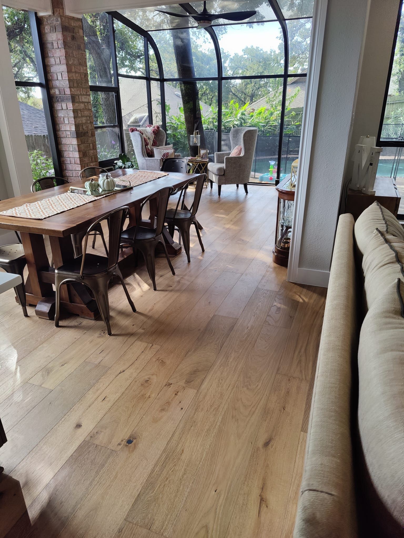 Dining area with a large wooden table, metal chairs, and floor-to-ceiling windows.
