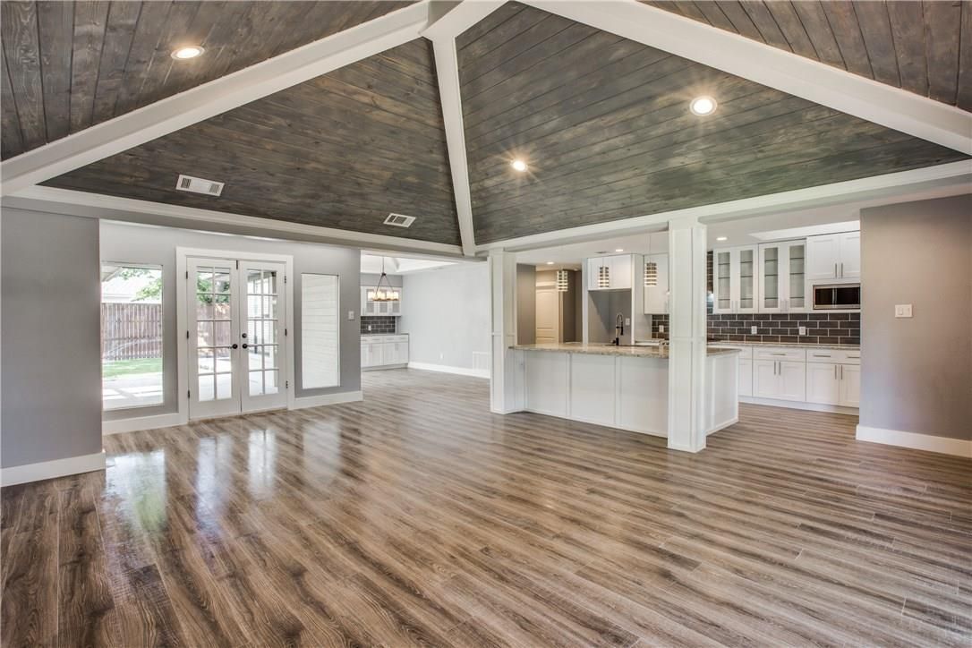 Spacious, modern interior with wood-look flooring, vaulted ceiling, and open kitchen.