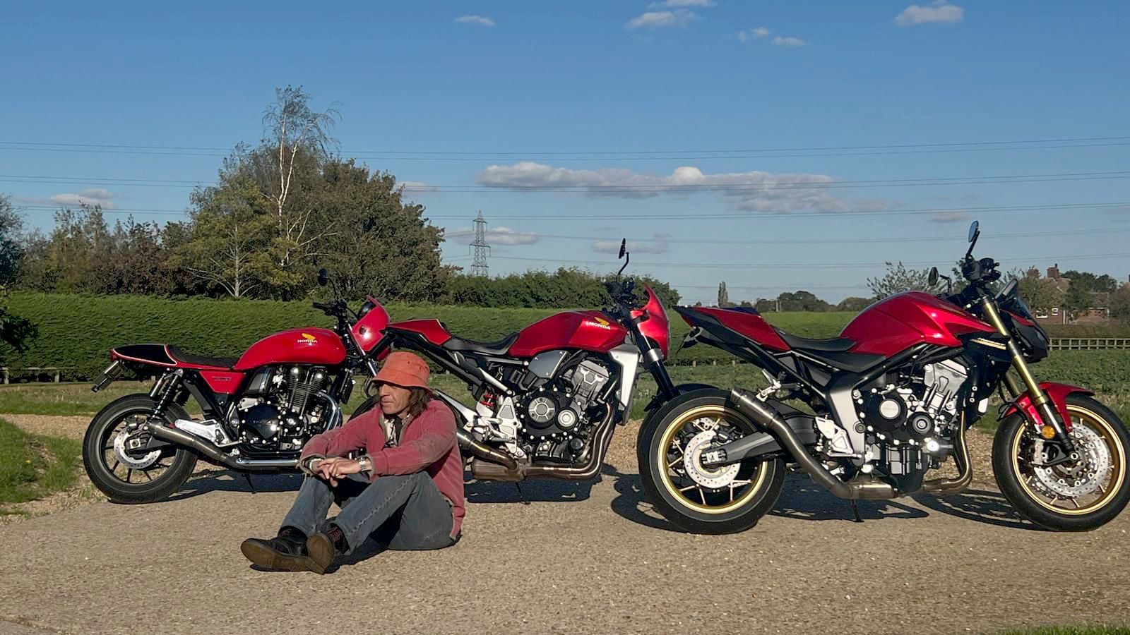 Three men with red motorcycles parked outdoors.