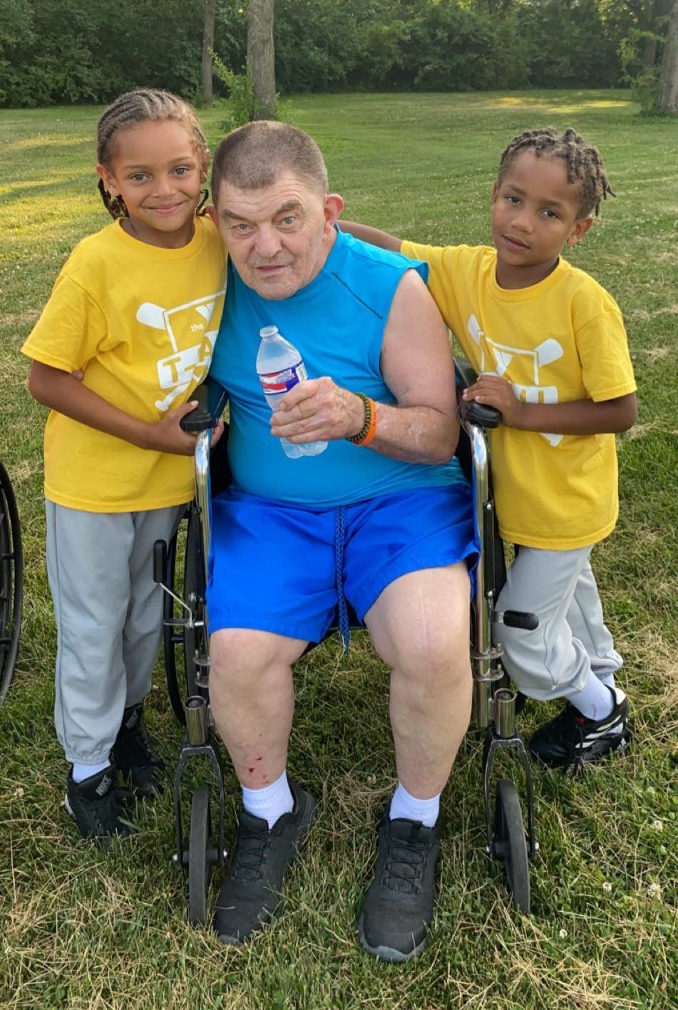 a man in a wheelchair holds a bottle of aquafina water