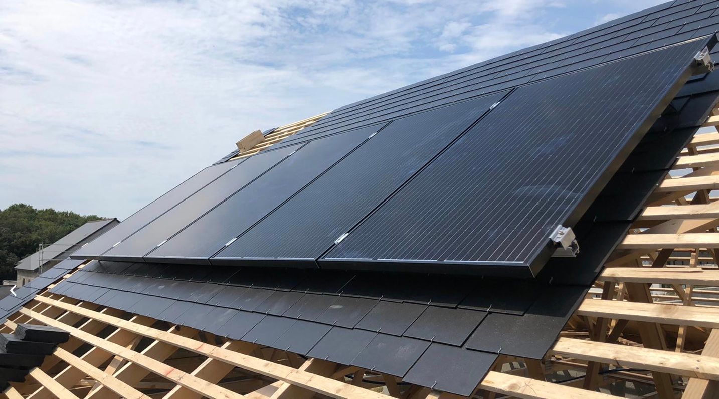 Des panneaux solaires noirs installés sur un toit en pente sous un ciel dégagé