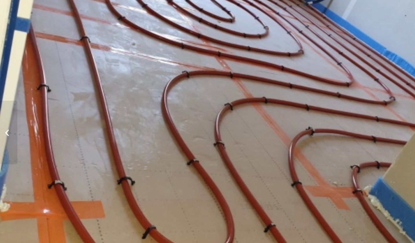 Des tubes rouges et noirs disposés en serpentins sur un panneau blanc incliné.