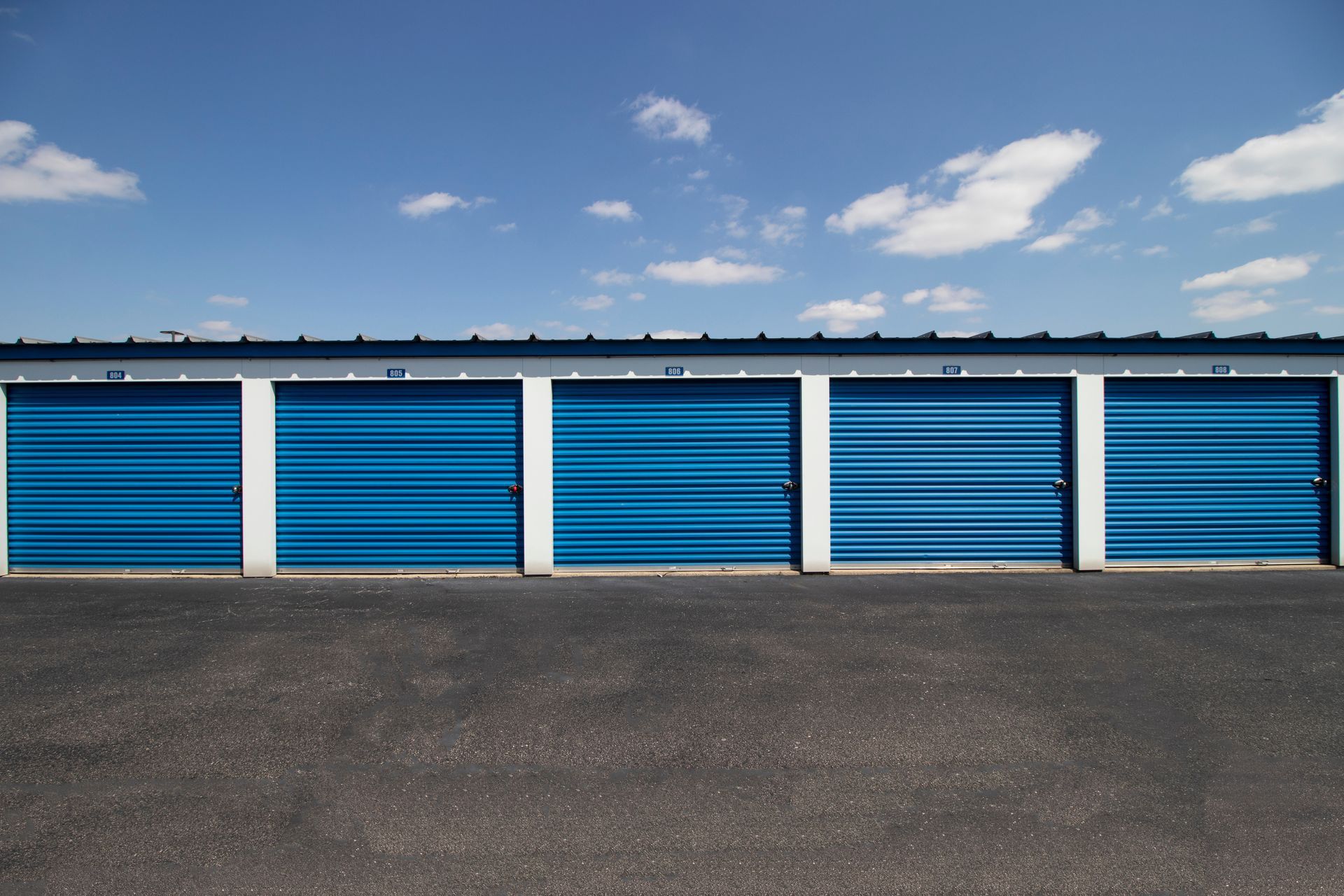 Blue storage units with white trim against a blue sky with clouds.