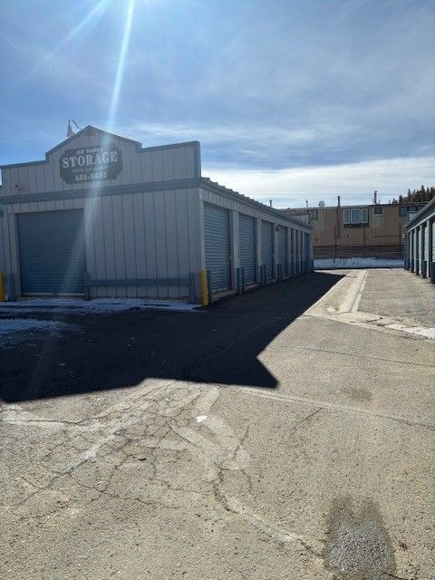 Storage units with closed gray doors under a partly cloudy sky.