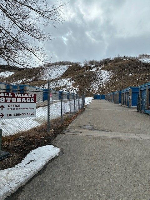 Exterior view of Ball Valley Storage, with storage units, fence, and snow-covered hill.