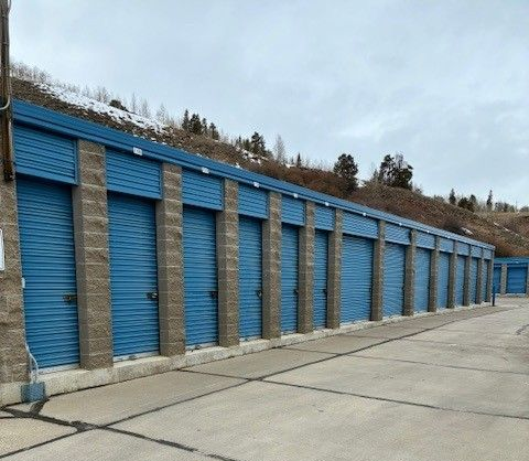 Boxes on a yellow hand truck in a storage unit facility with yellow doors.