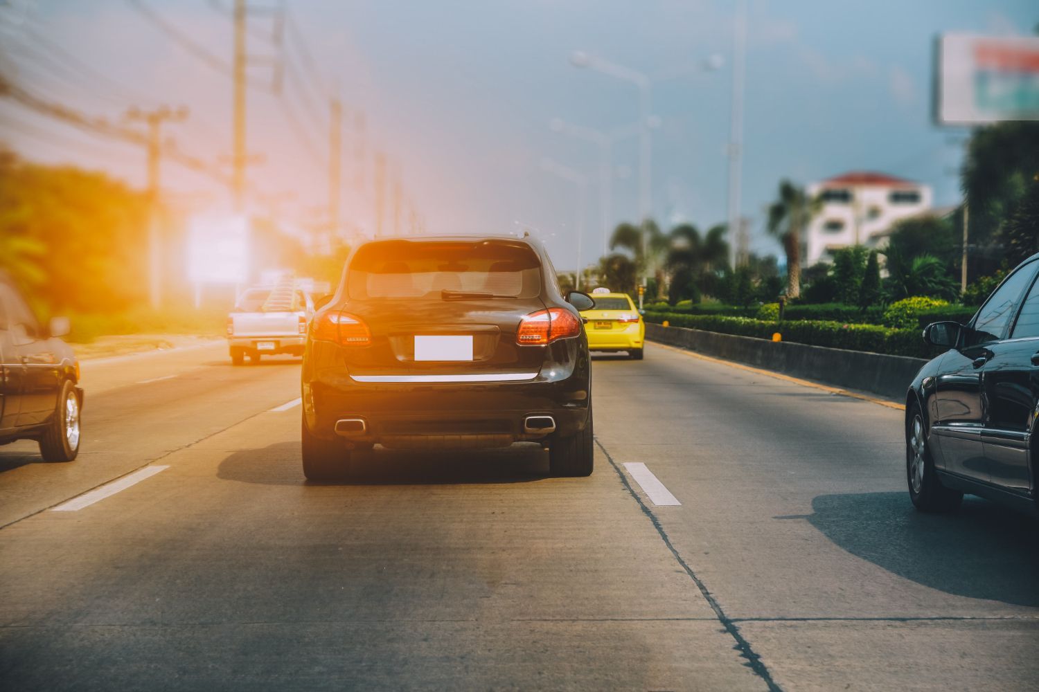 A black car is driving down a highway next to a yellow car.