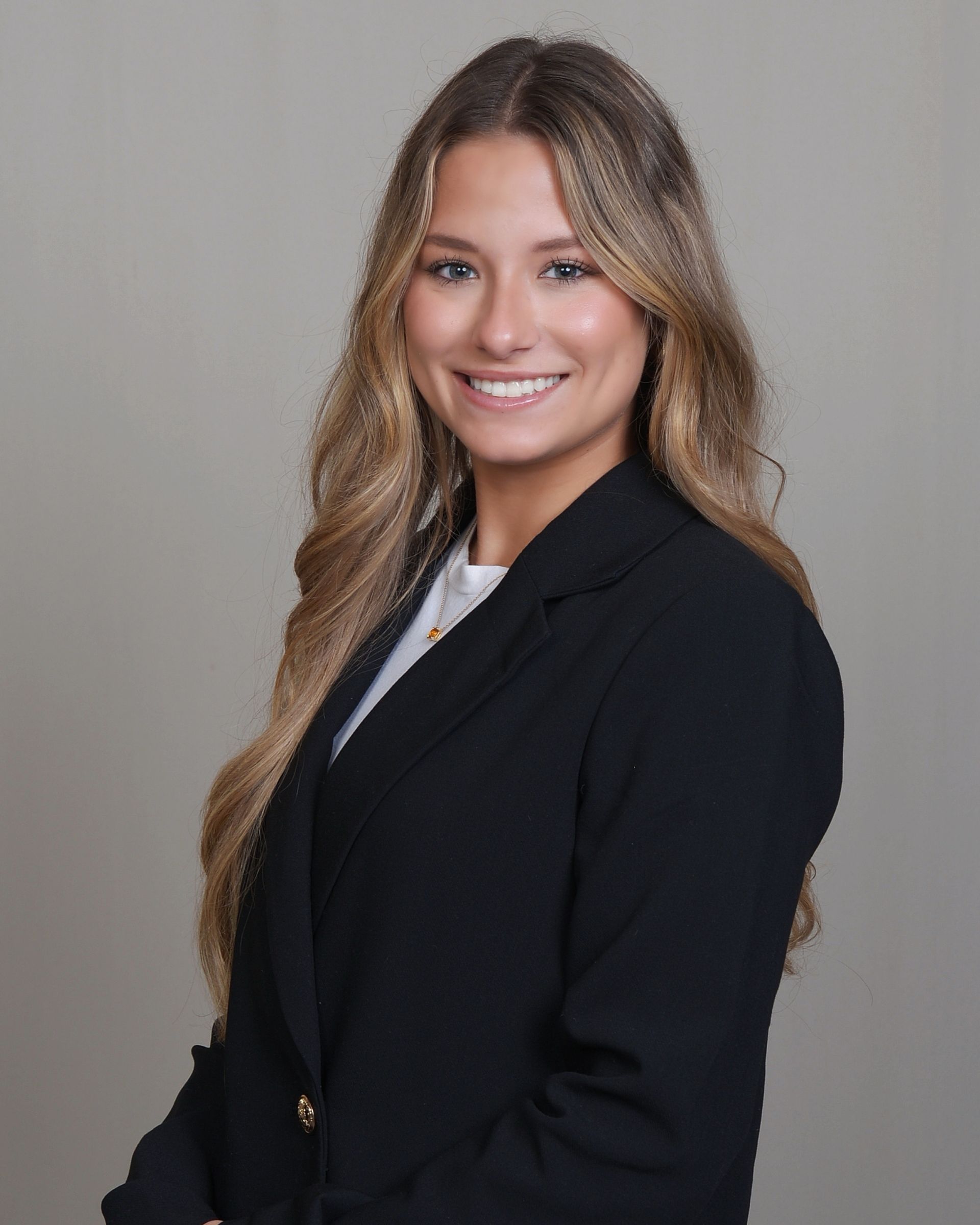Zoey in a black jacket and white shirt smiling for the camera.