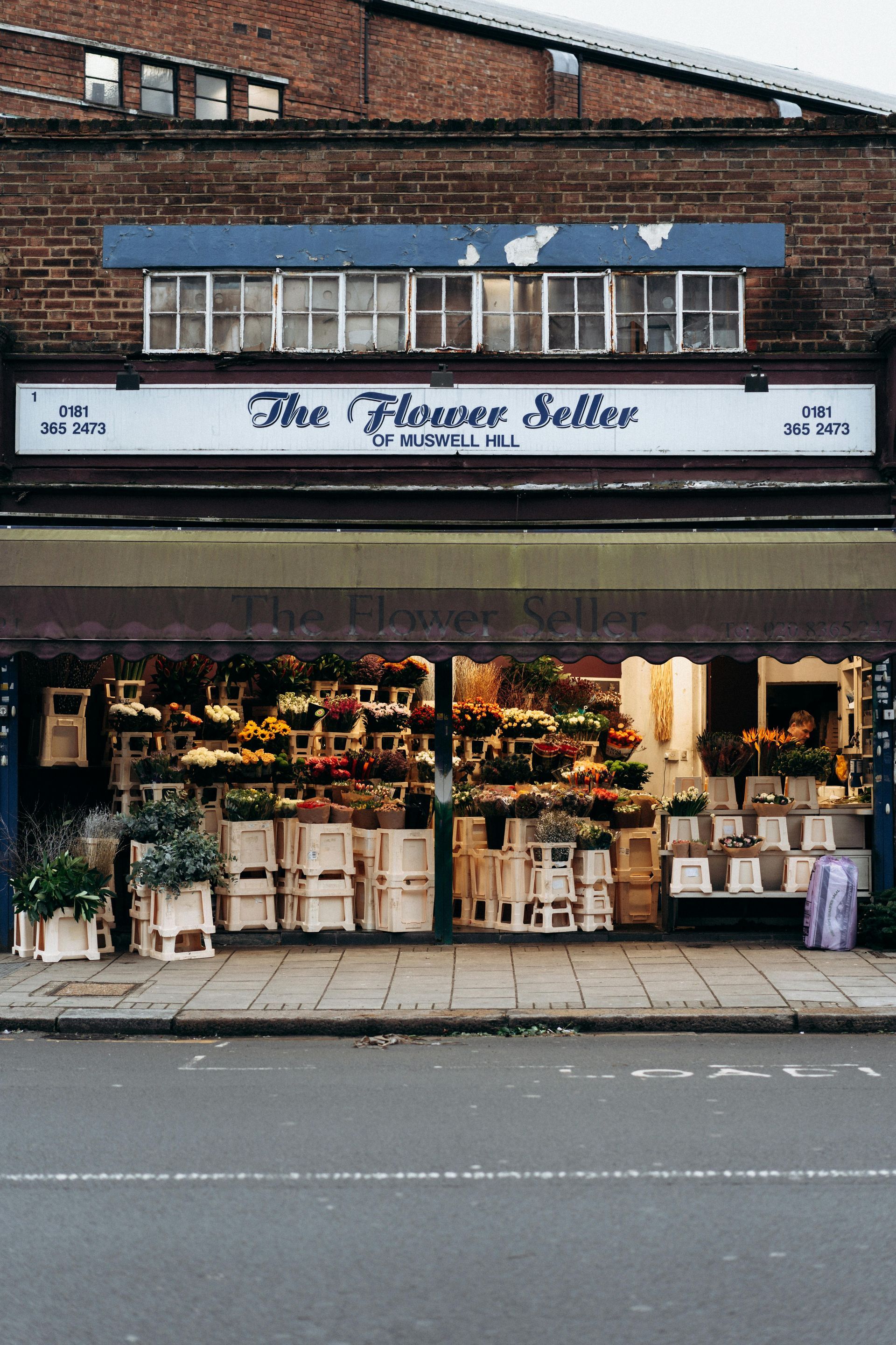 A brick building with a sign that says the flower seller