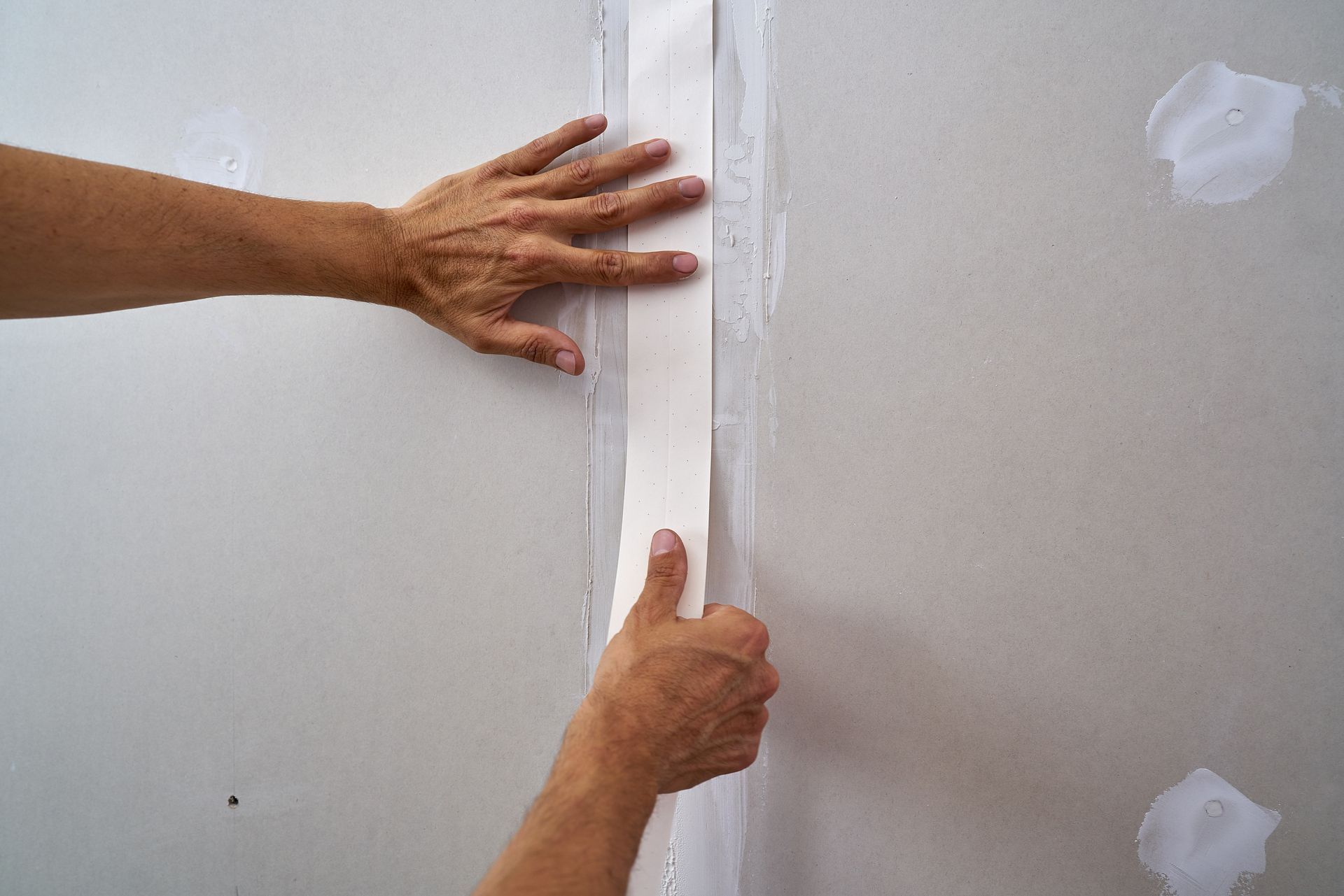 A person is taping a corner of a wall with tape.
