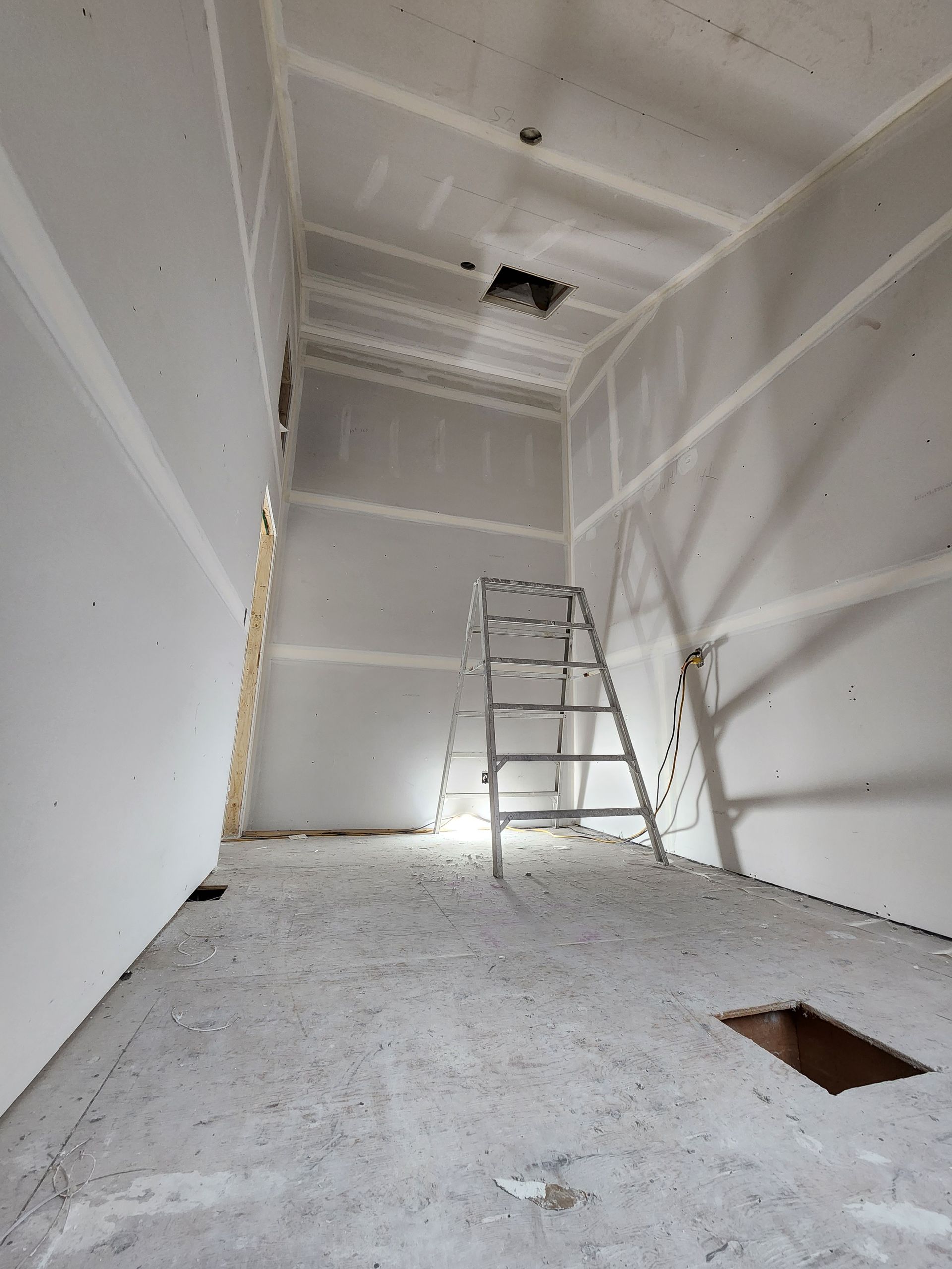 an empty room with a ladder and a hole in the floor