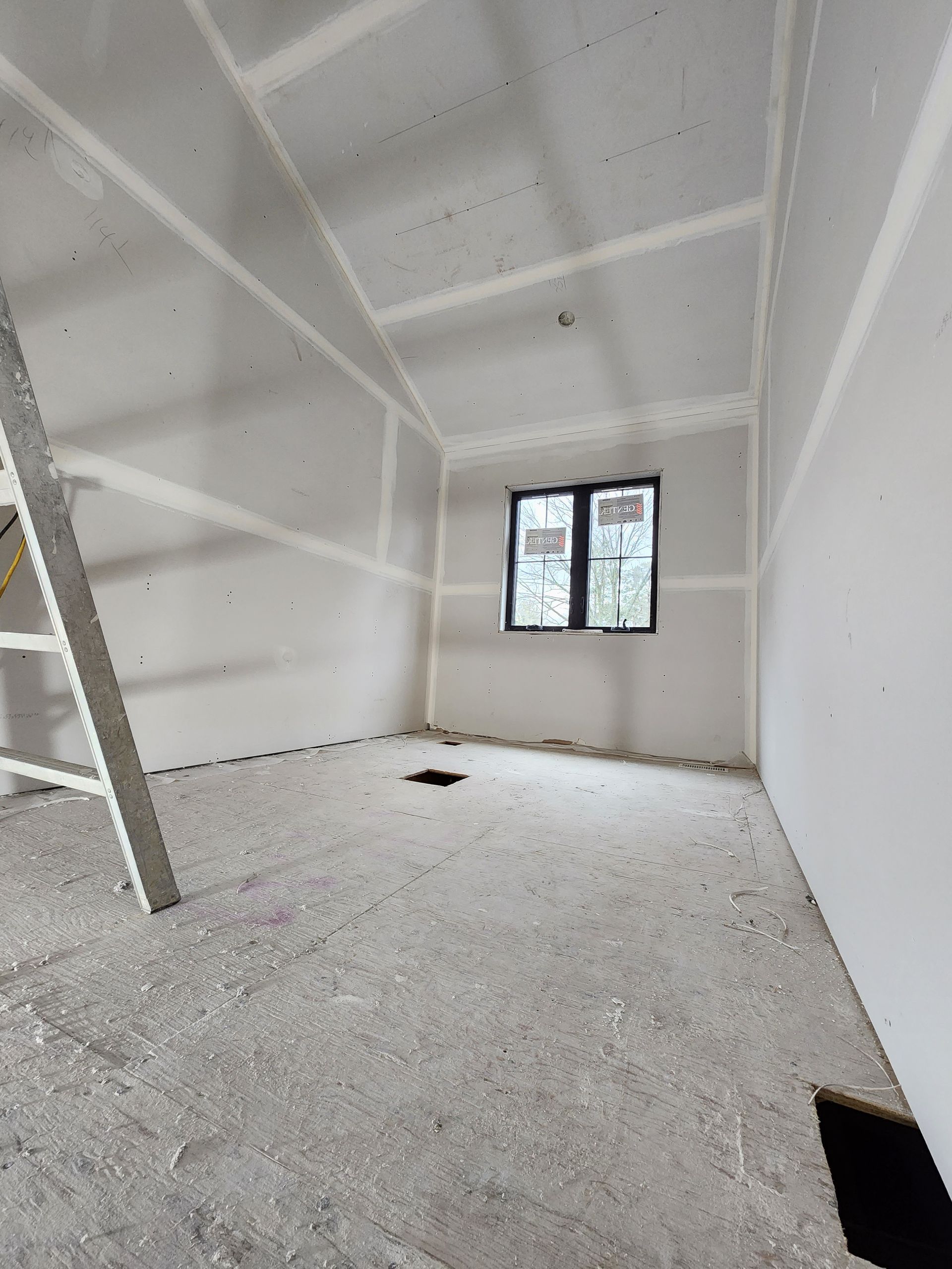an empty room with a ladder and a window