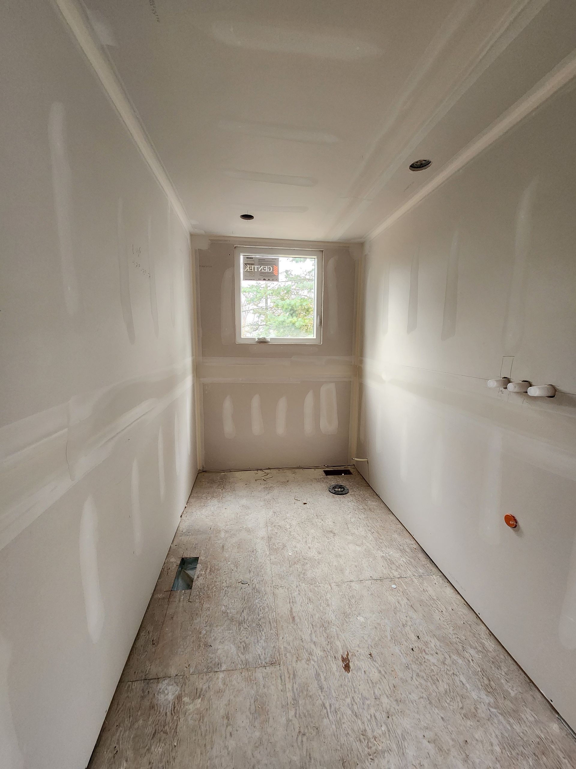 an empty room with a window and drywall on the walls