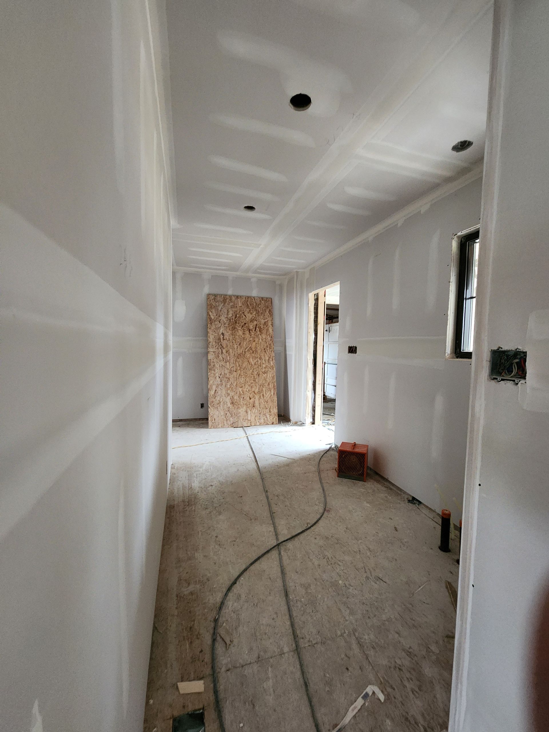 a long hallway with drywall on the walls and a door .