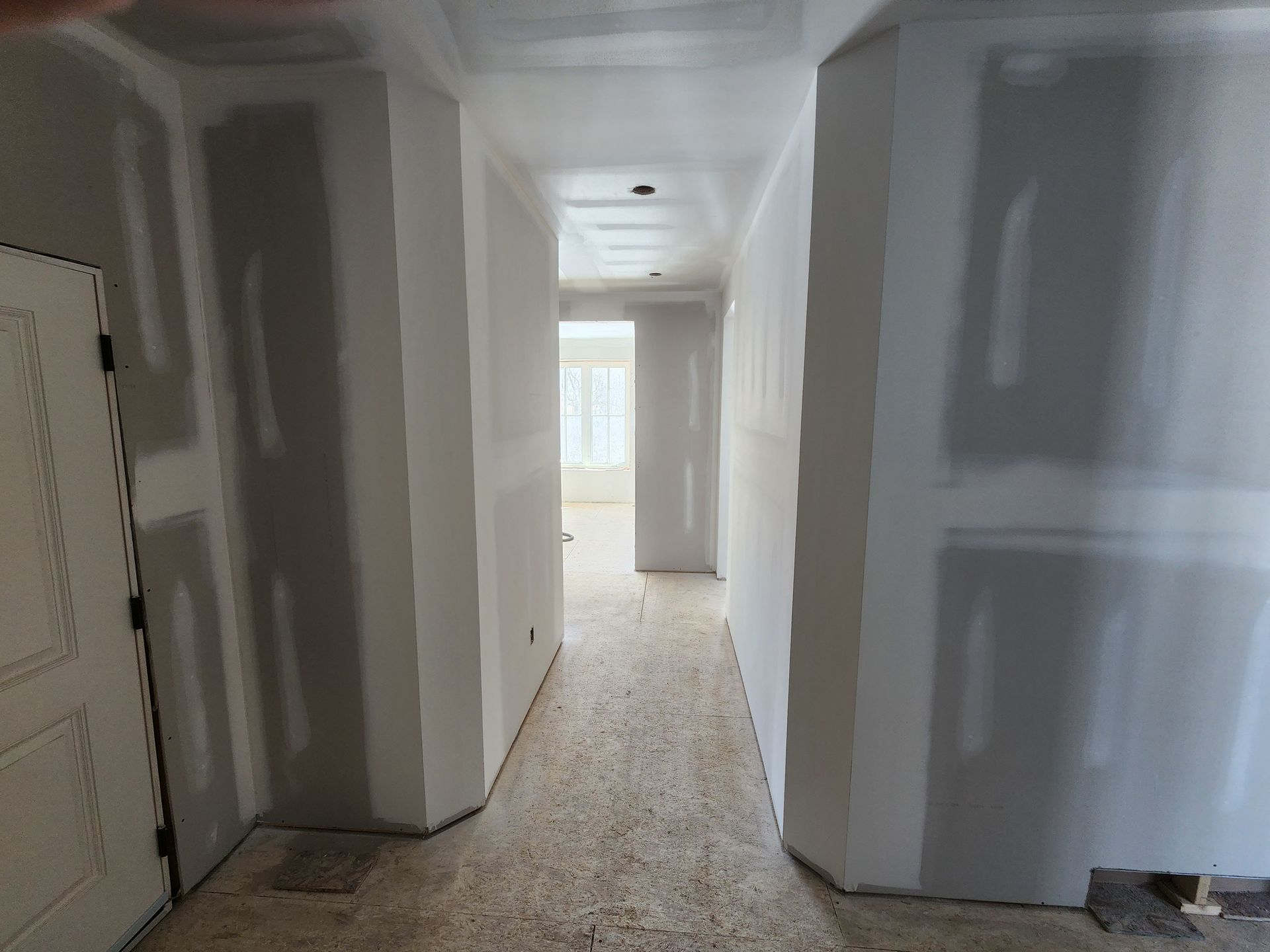 a hallway with drywall on the walls and a door