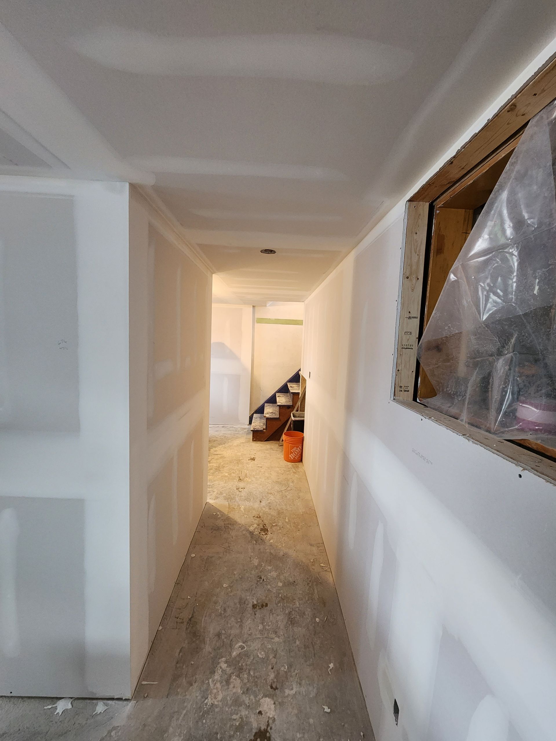 a hallway leading to a staircase in a basement under construction .