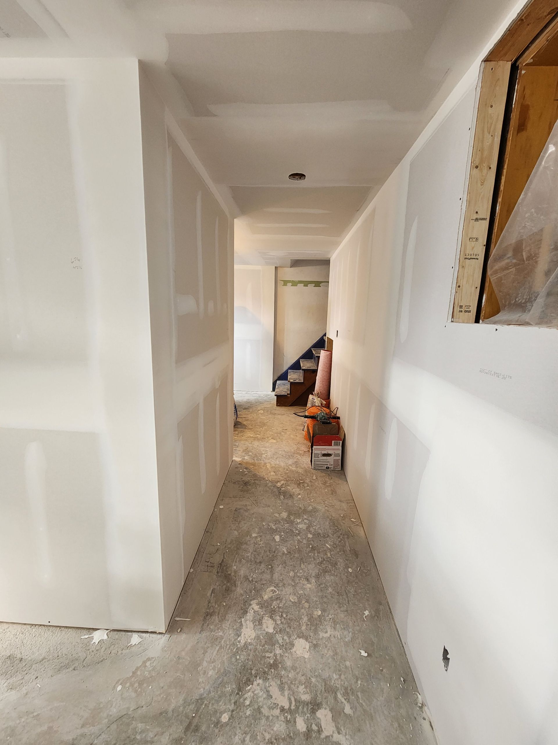 a hallway in a house under construction with a staircase in the background .