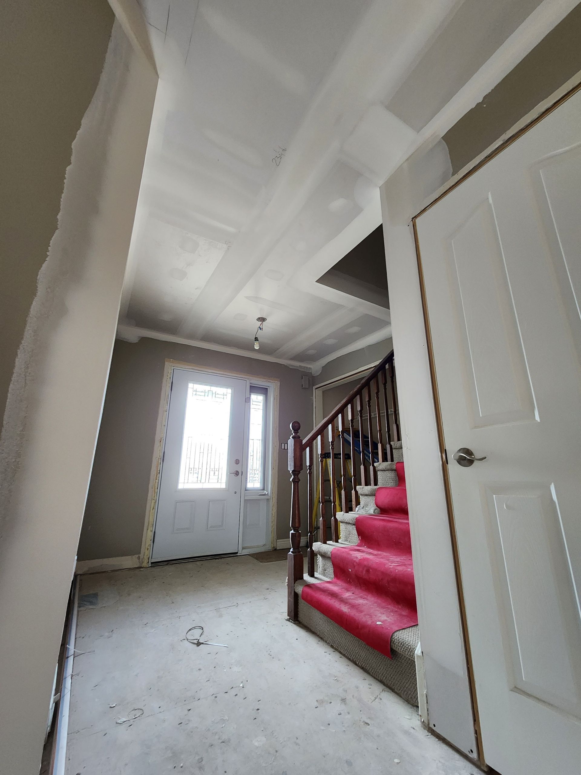 a hallway with stairs and a white door