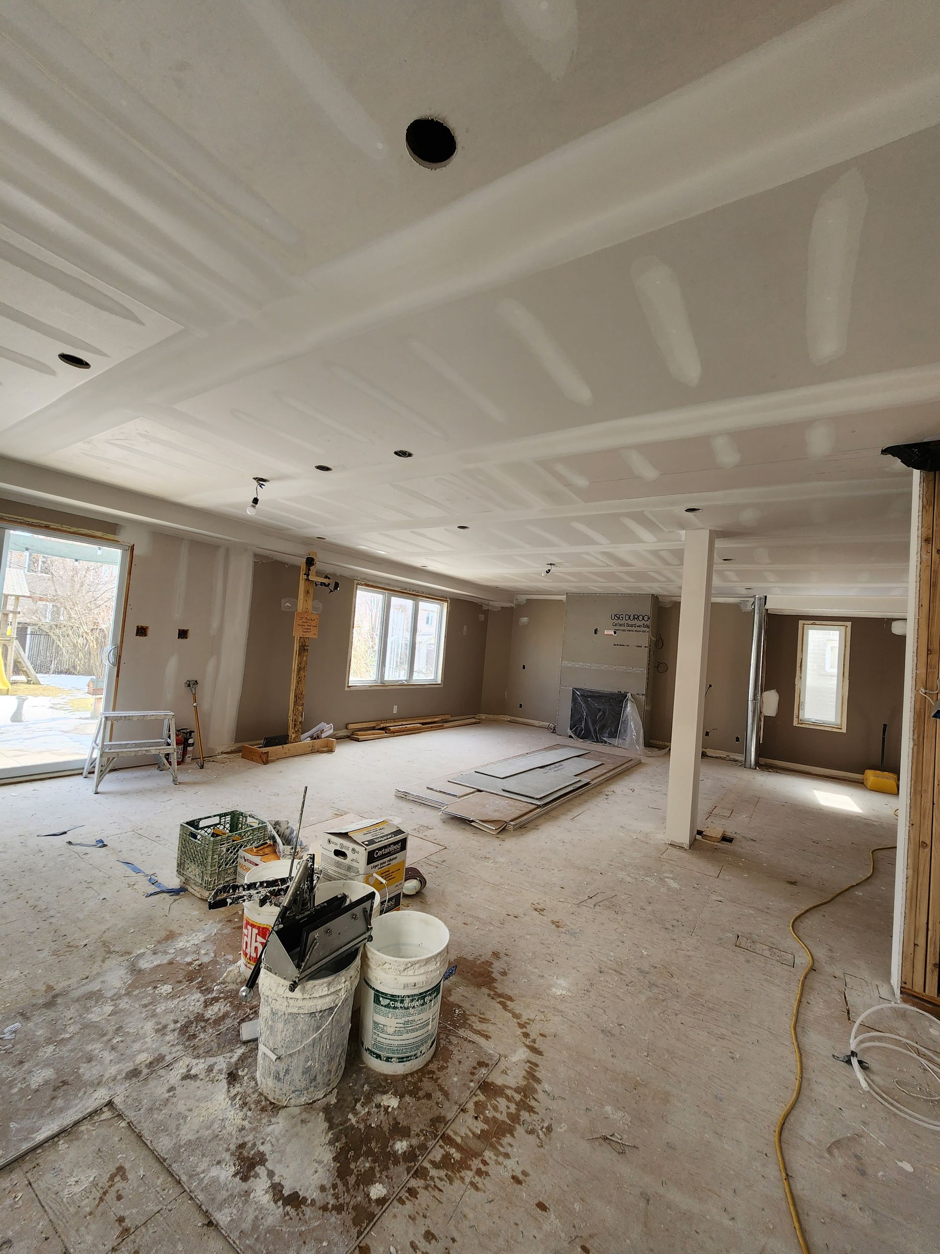 a large empty room with buckets of paint on the floor .