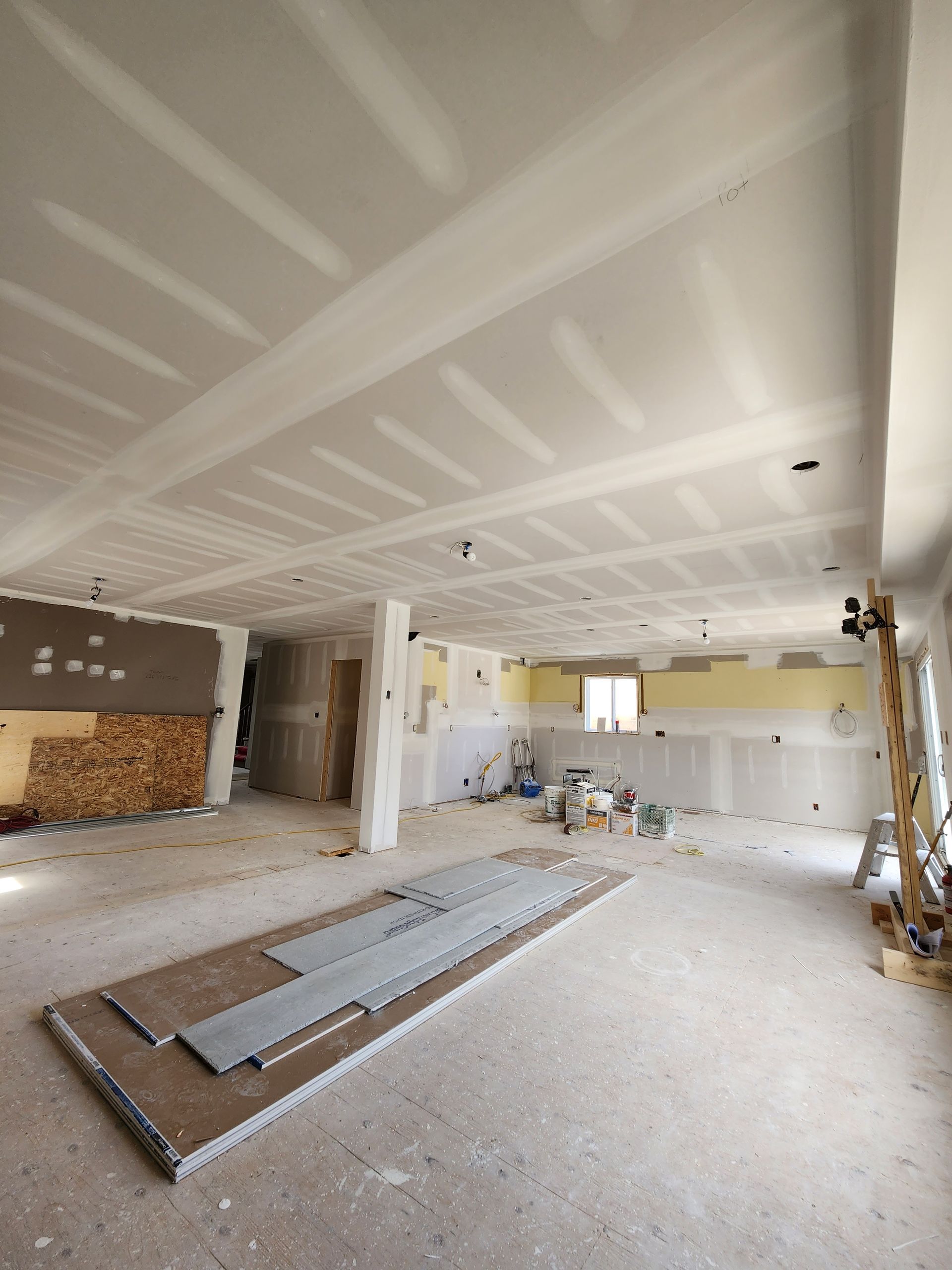 an empty room with a lot of drywall and a ladder