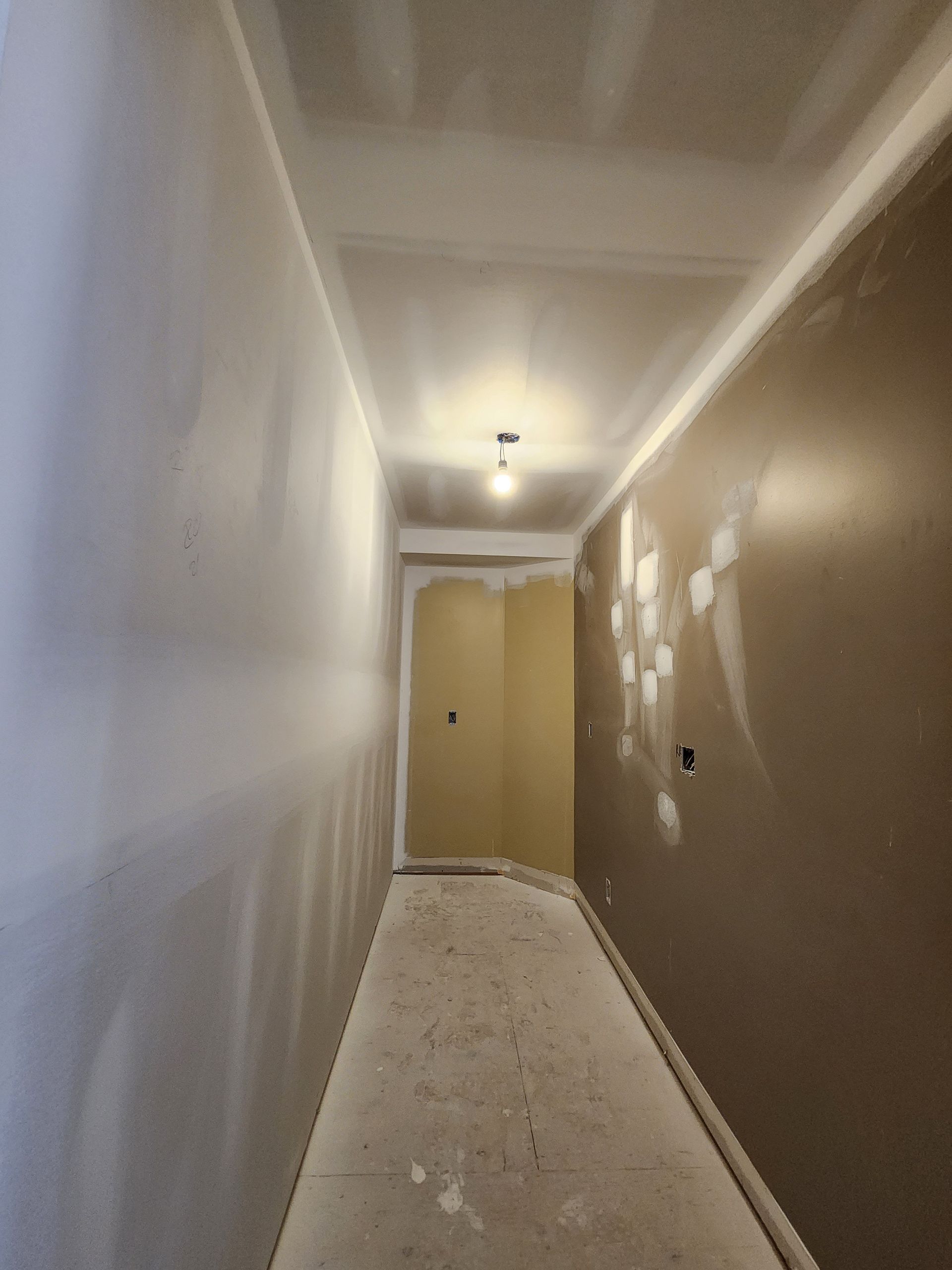 an empty hallway with a door in the corner and a light on the ceiling .