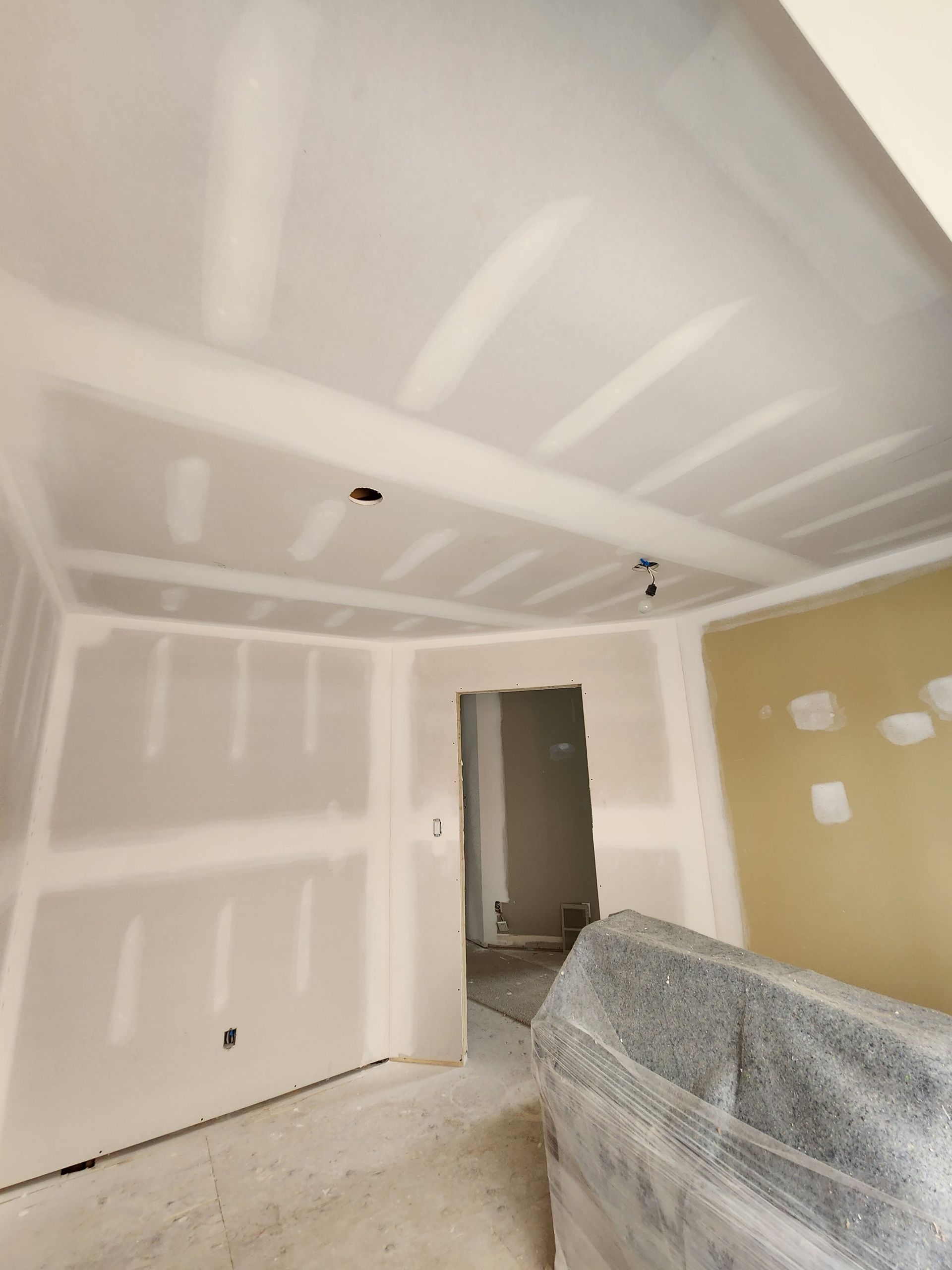 a room that is being remodeled with a couch wrapped in plastic