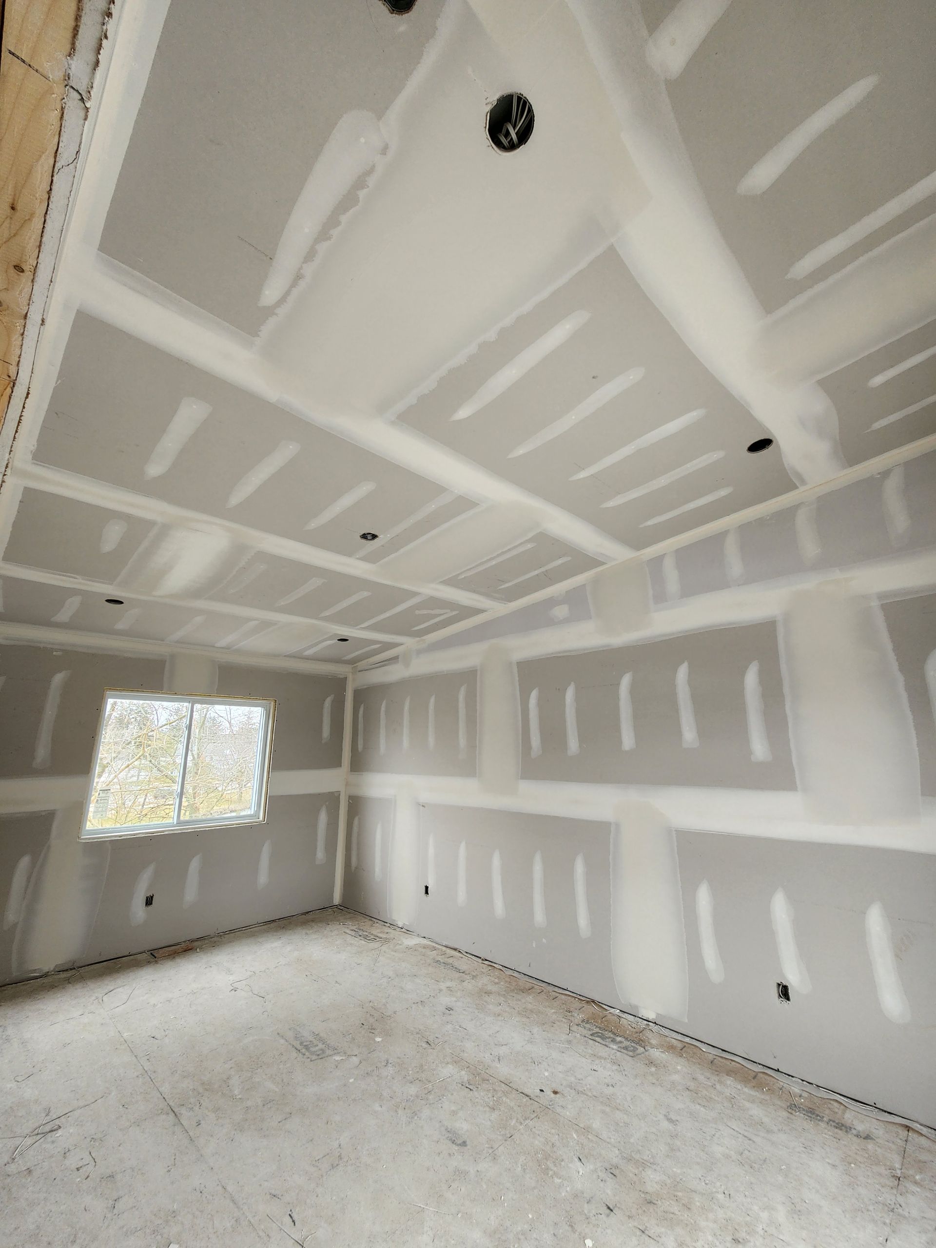 an empty room with drywall and a window