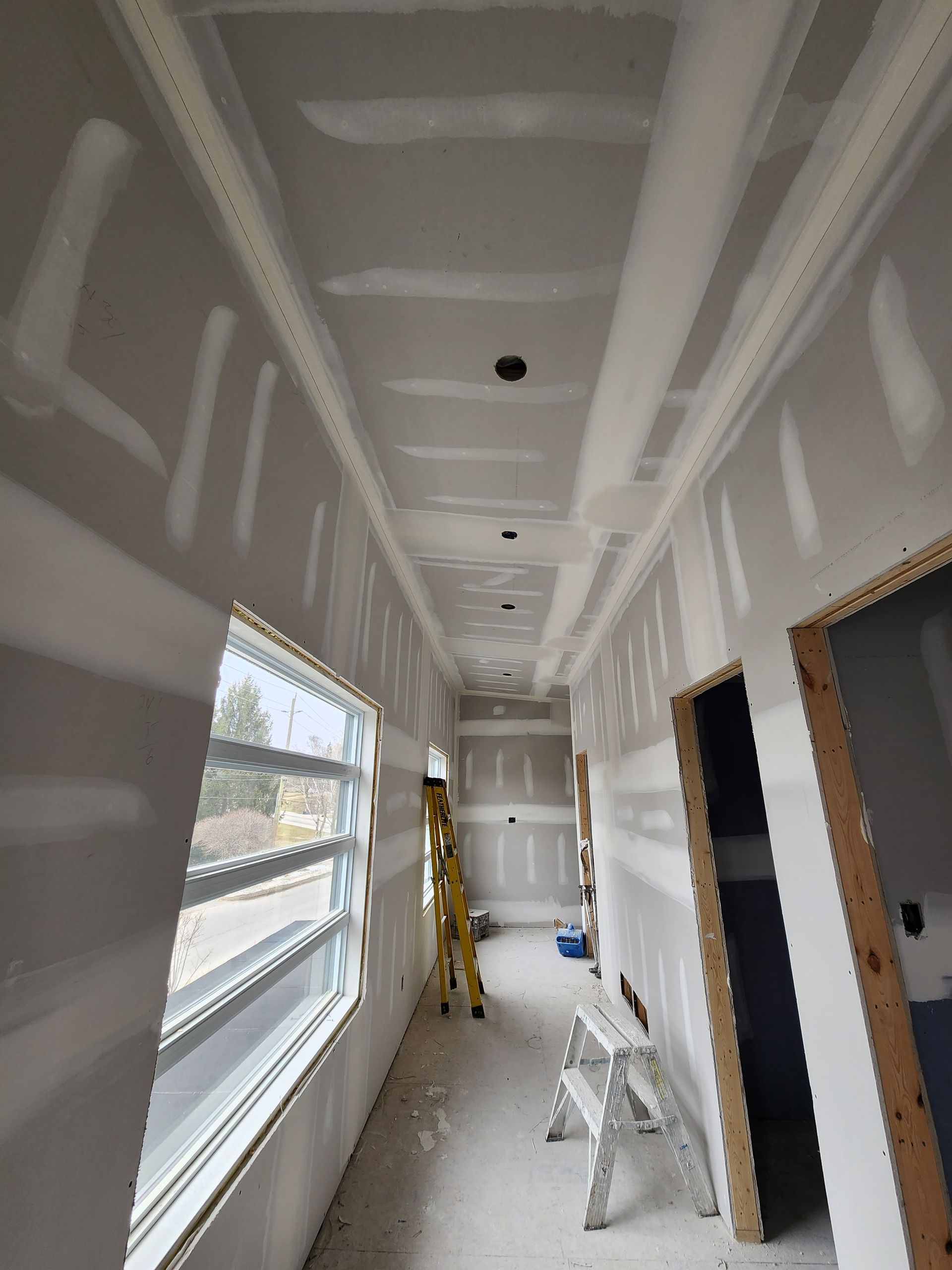 a long hallway with a ladder in the middle of it .