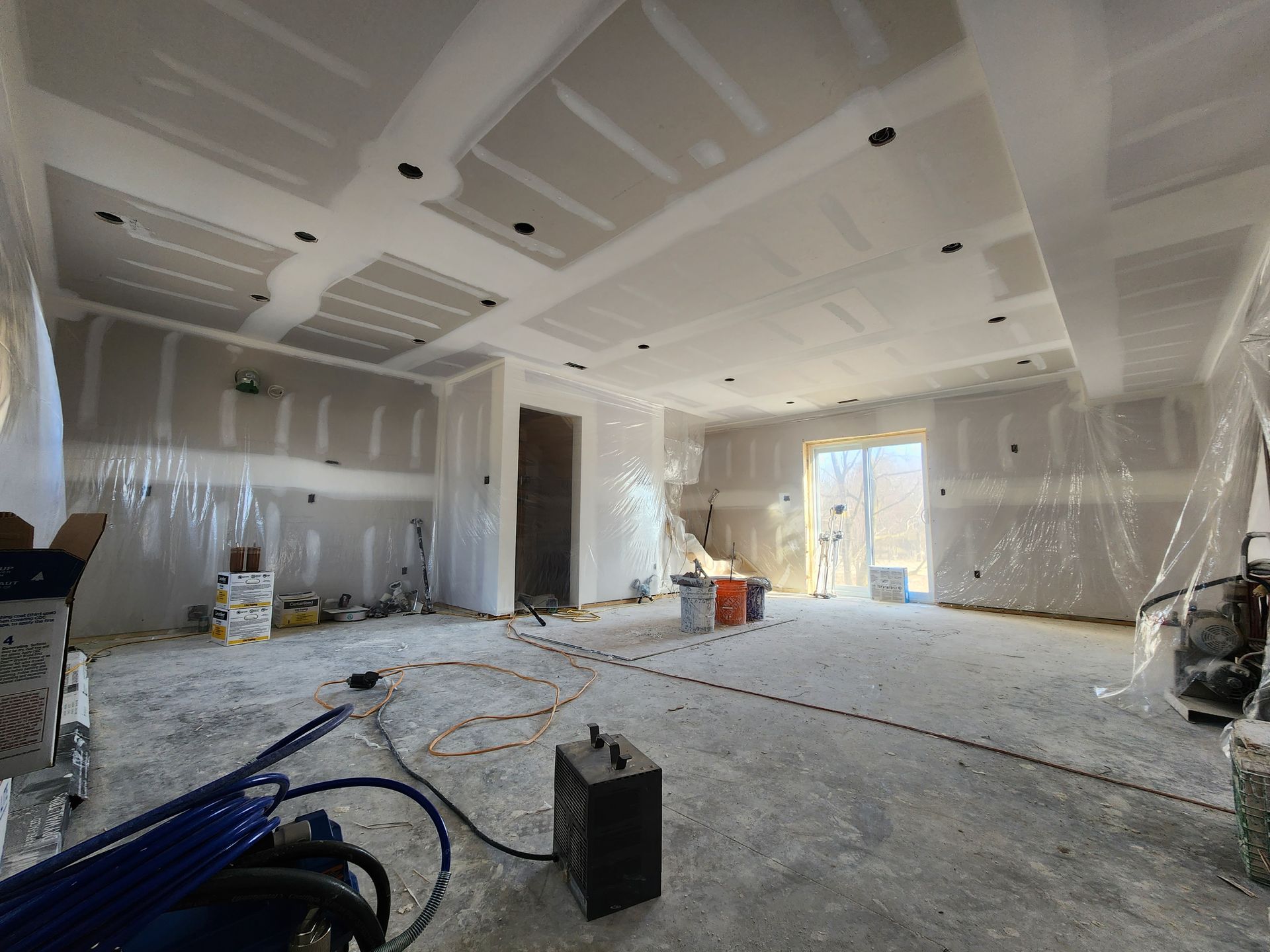 a large room in a house under construction with a heater on the floor .