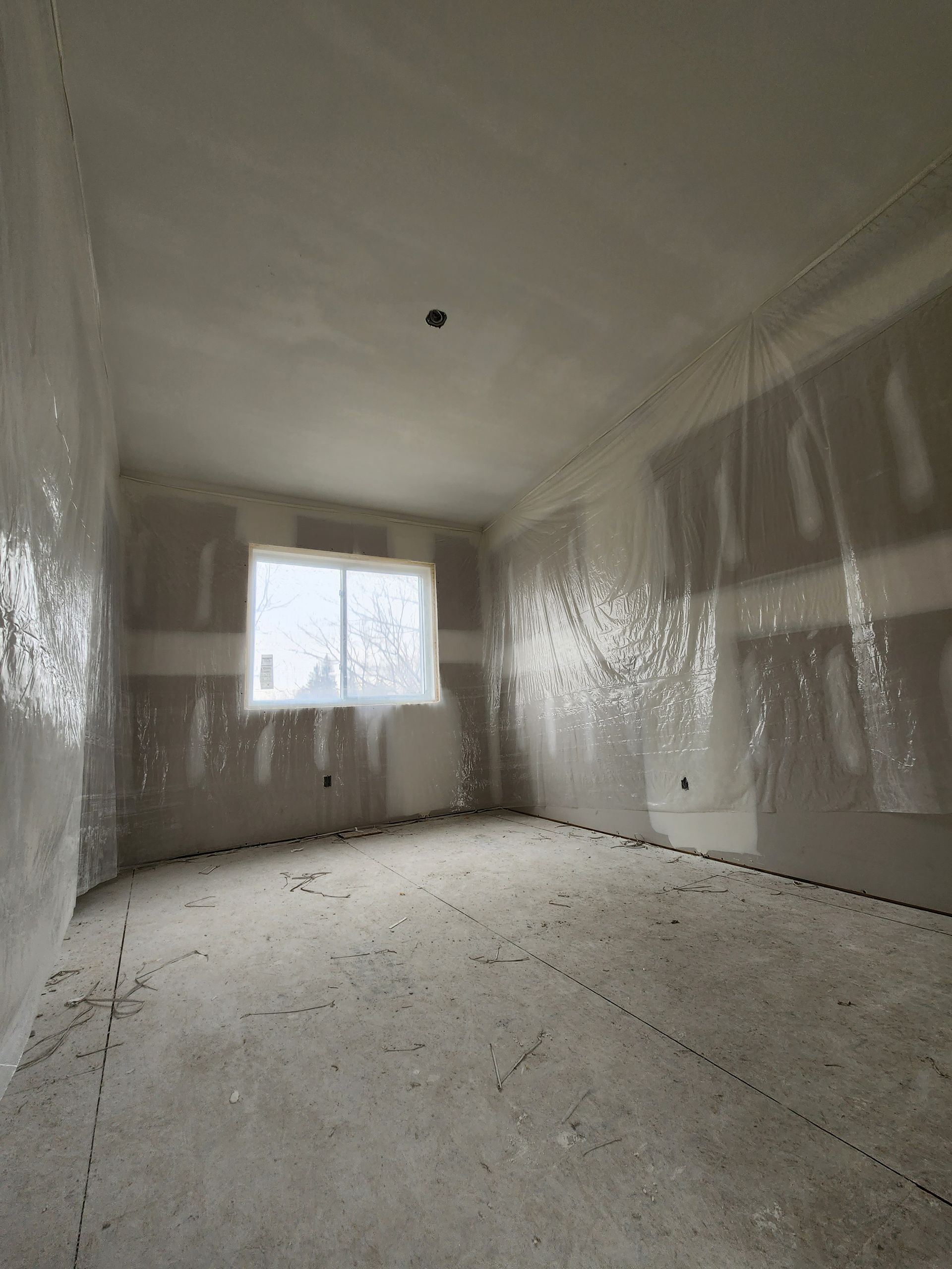 an empty room with drywall on the walls and a window .