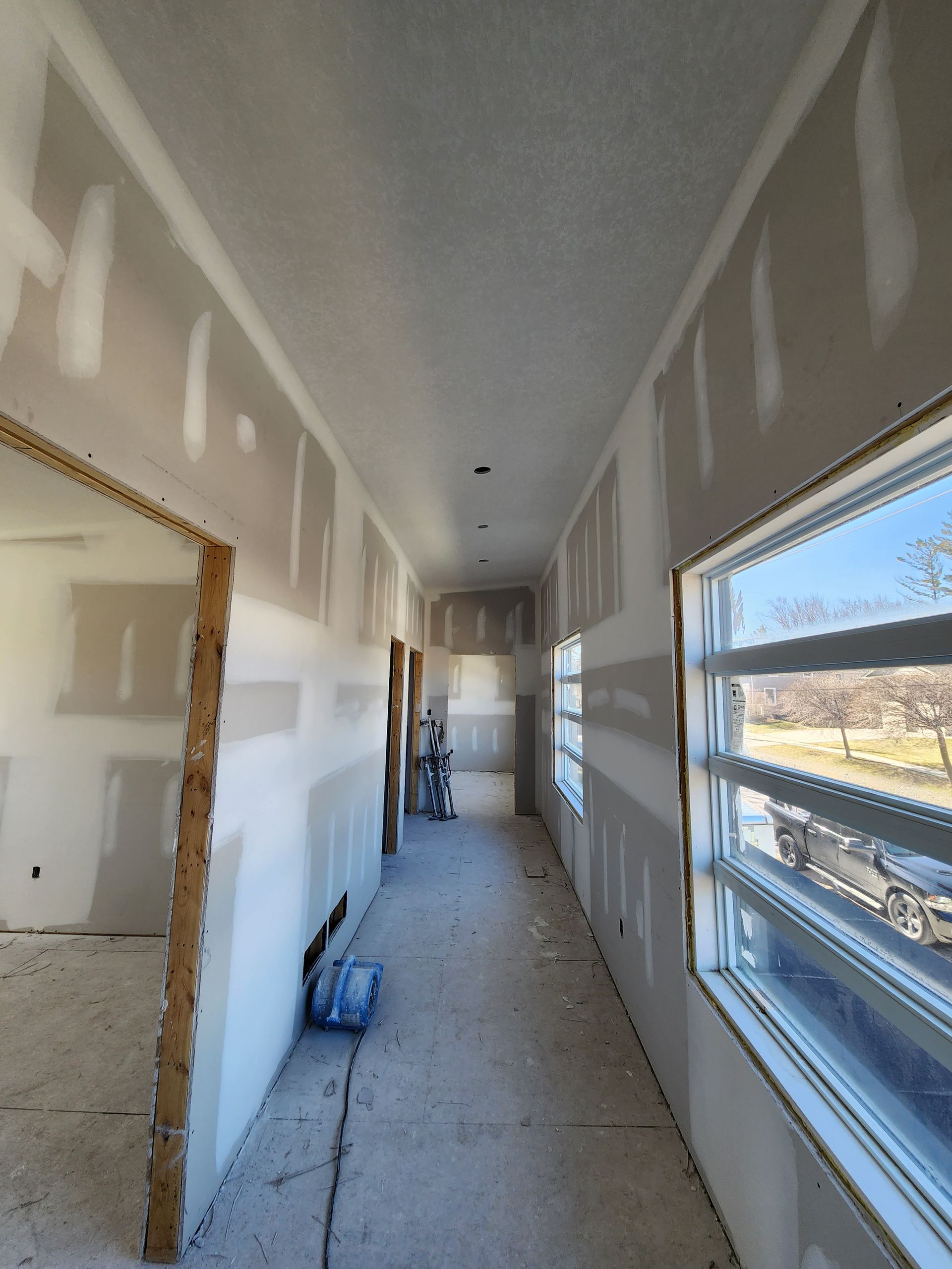 a long hallway with a lot of windows and drywall on the walls