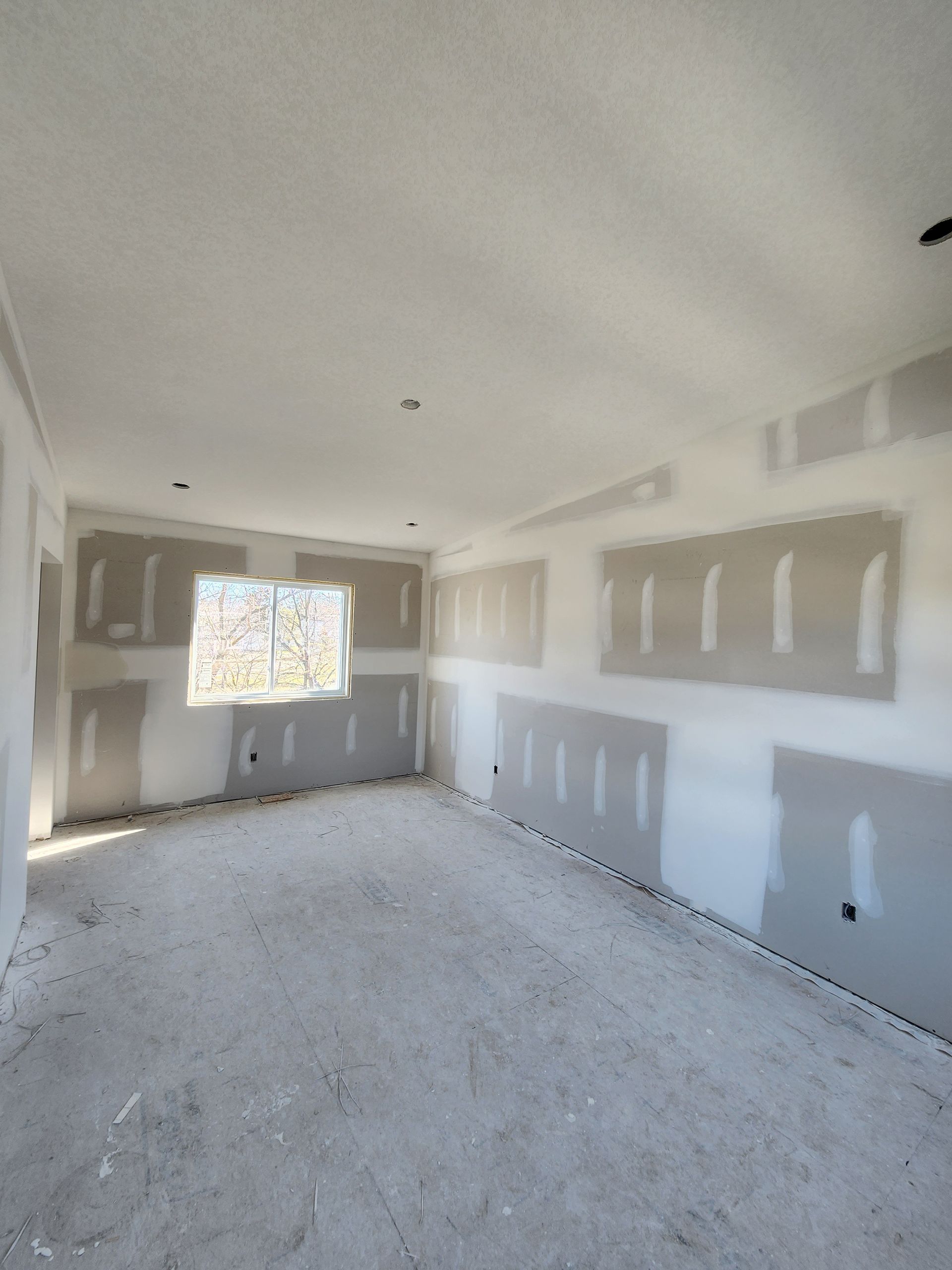 an empty room with drywall and a window