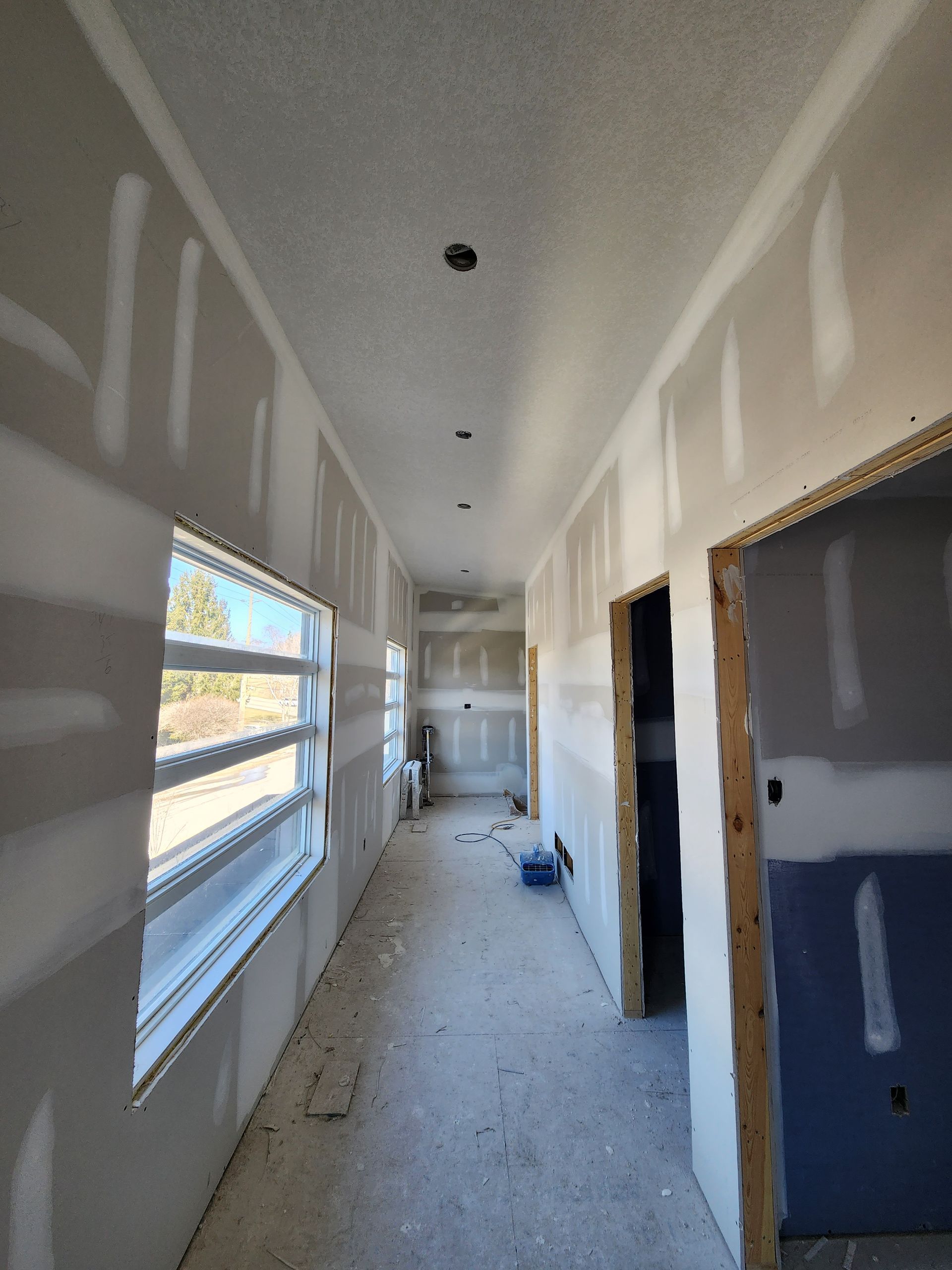 a long hallway with a lot of windows and drywall on the walls