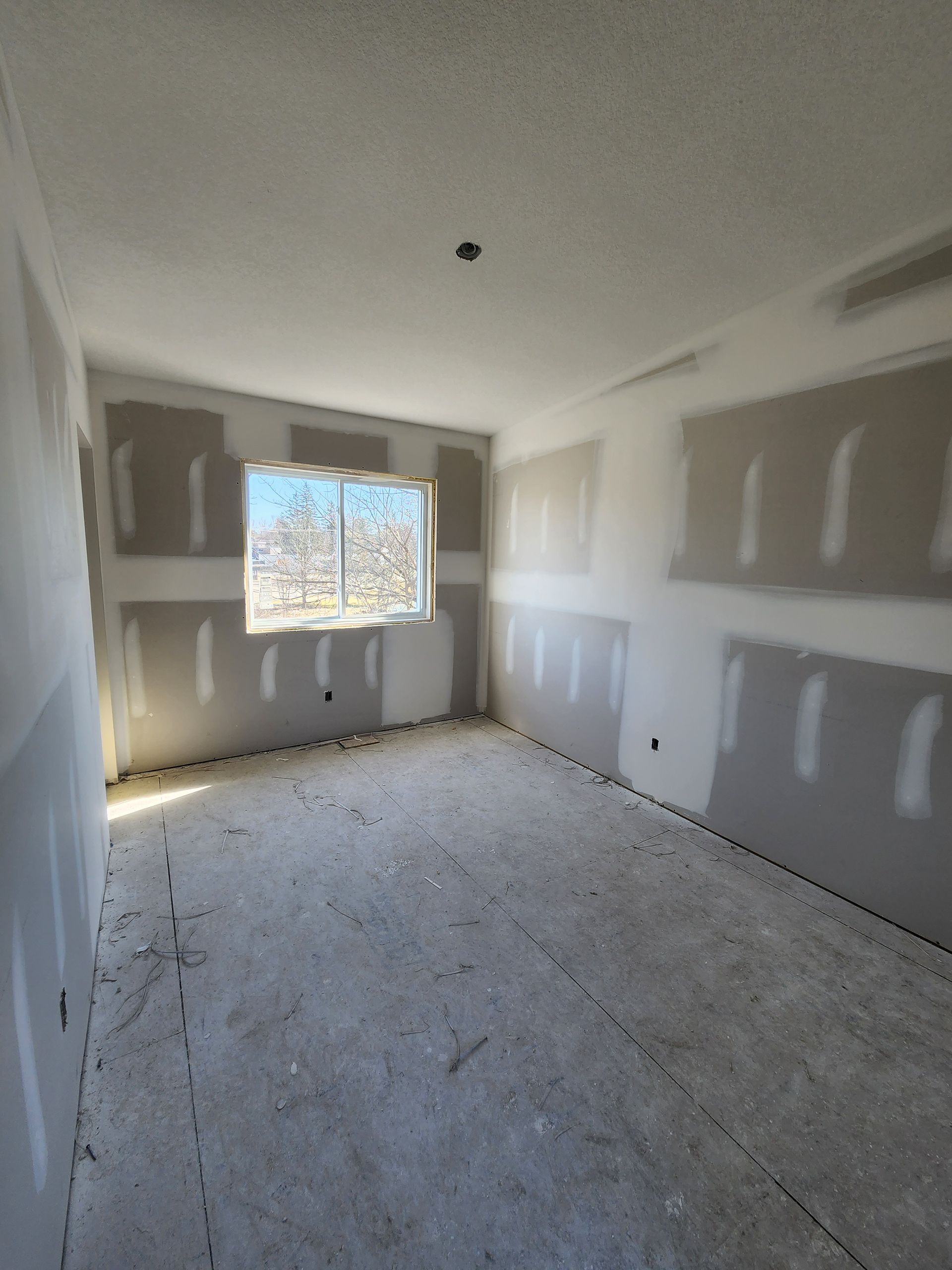 an empty room with drywall and a window