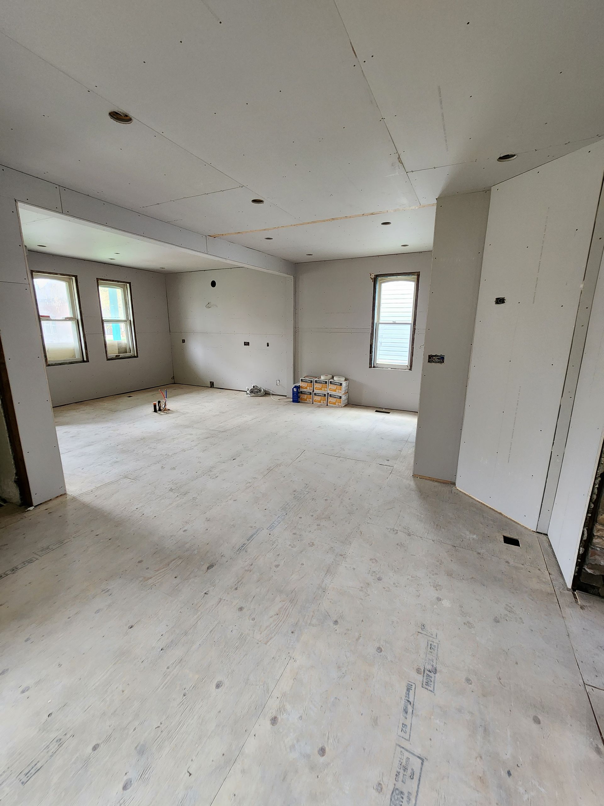 a large empty room with a lot of windows and drywall .