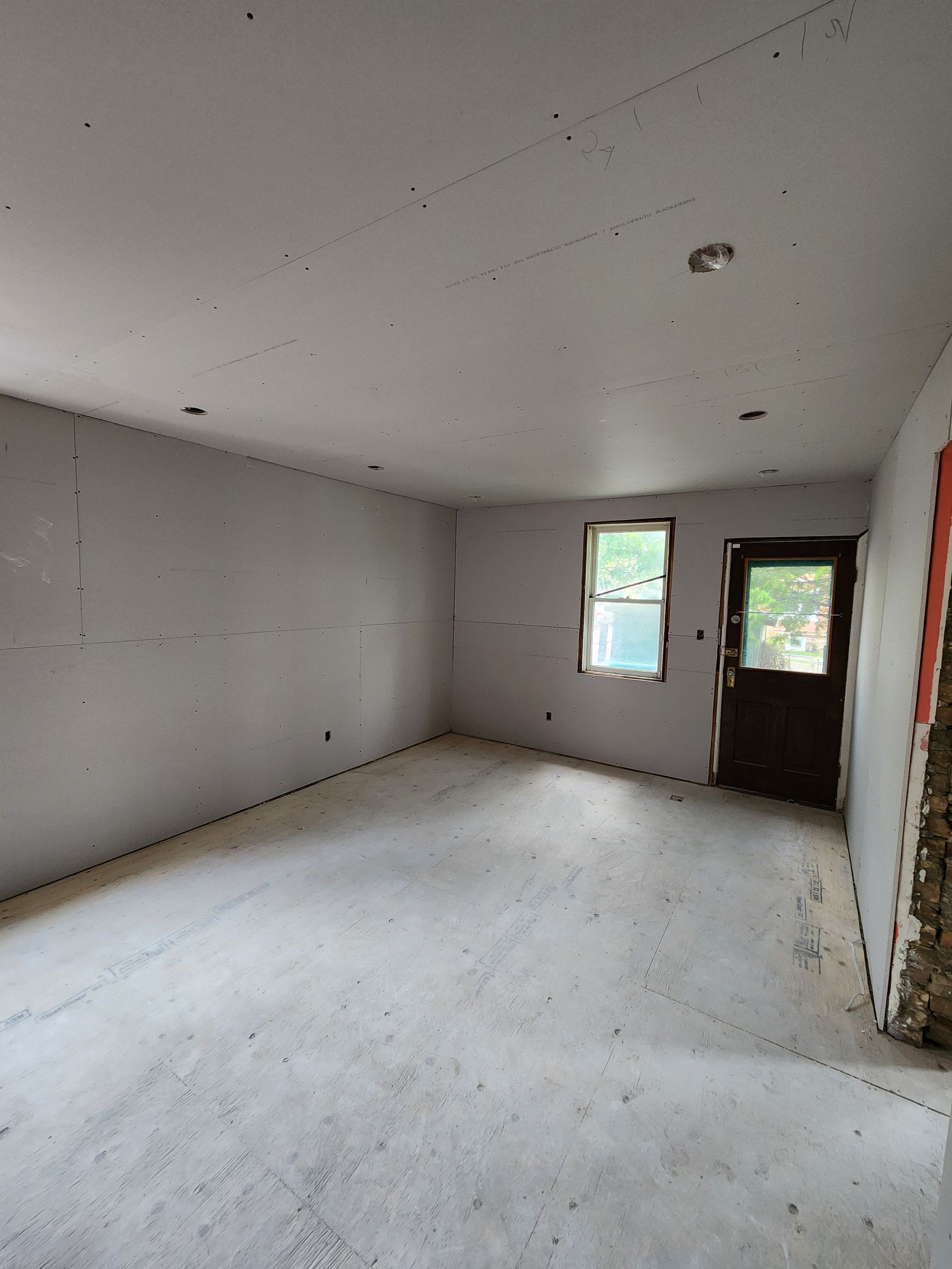 an empty room with a door and two windows