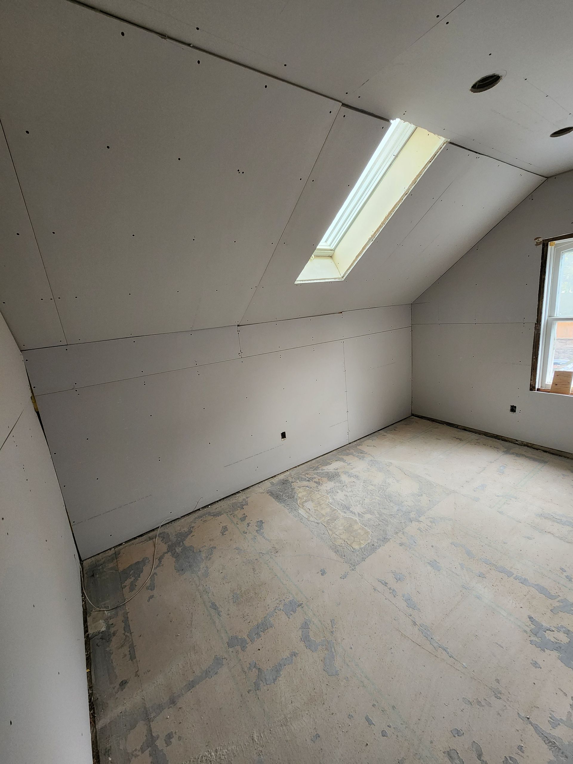 an empty room with a skylight in the ceiling and a window .