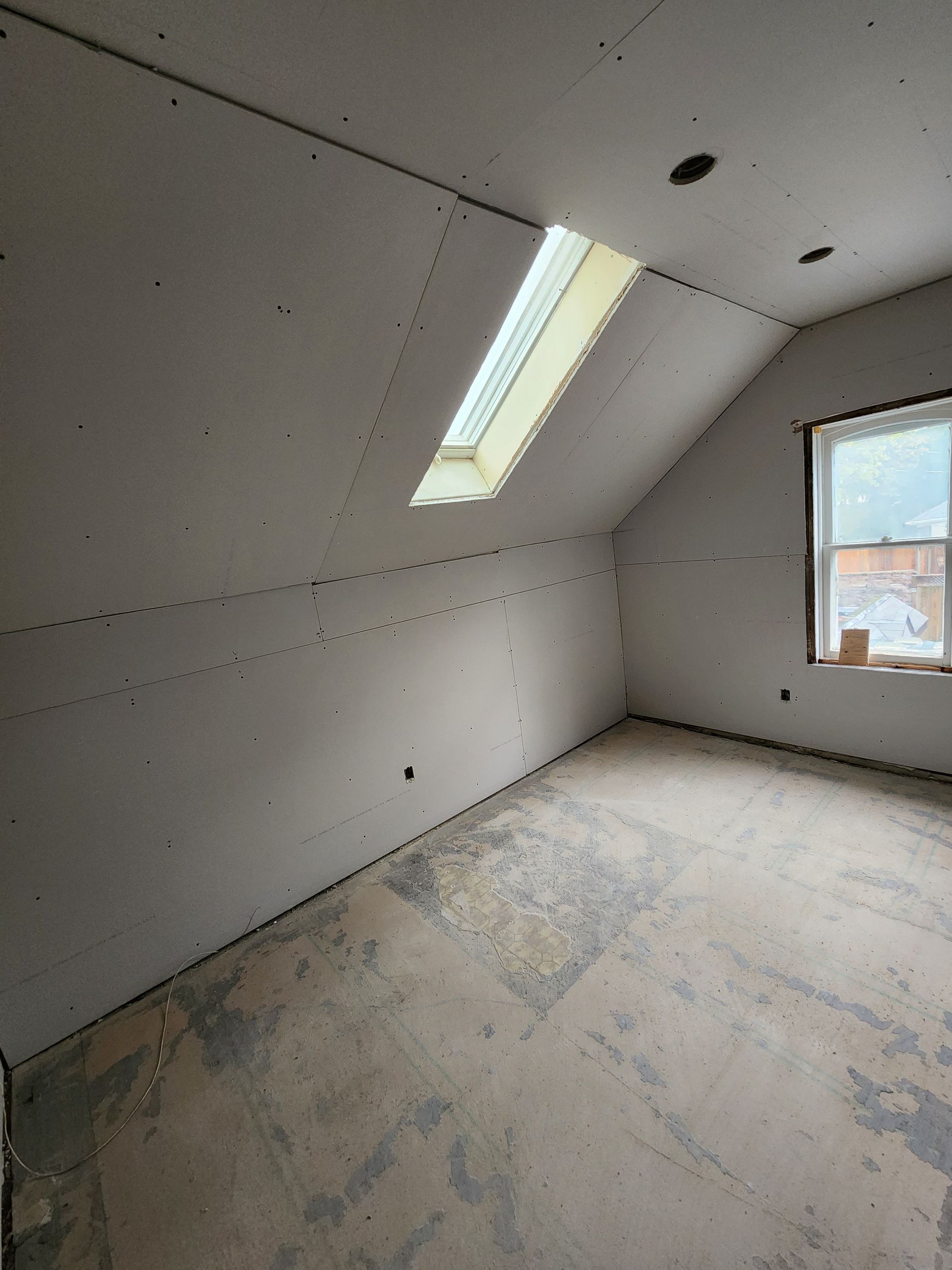 an empty room with a skylight and a window .