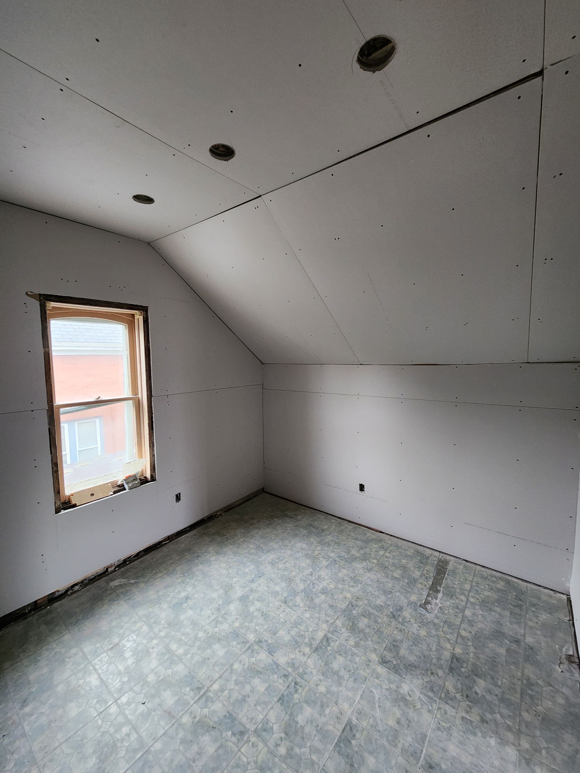 an empty room with a window and drywall on the walls