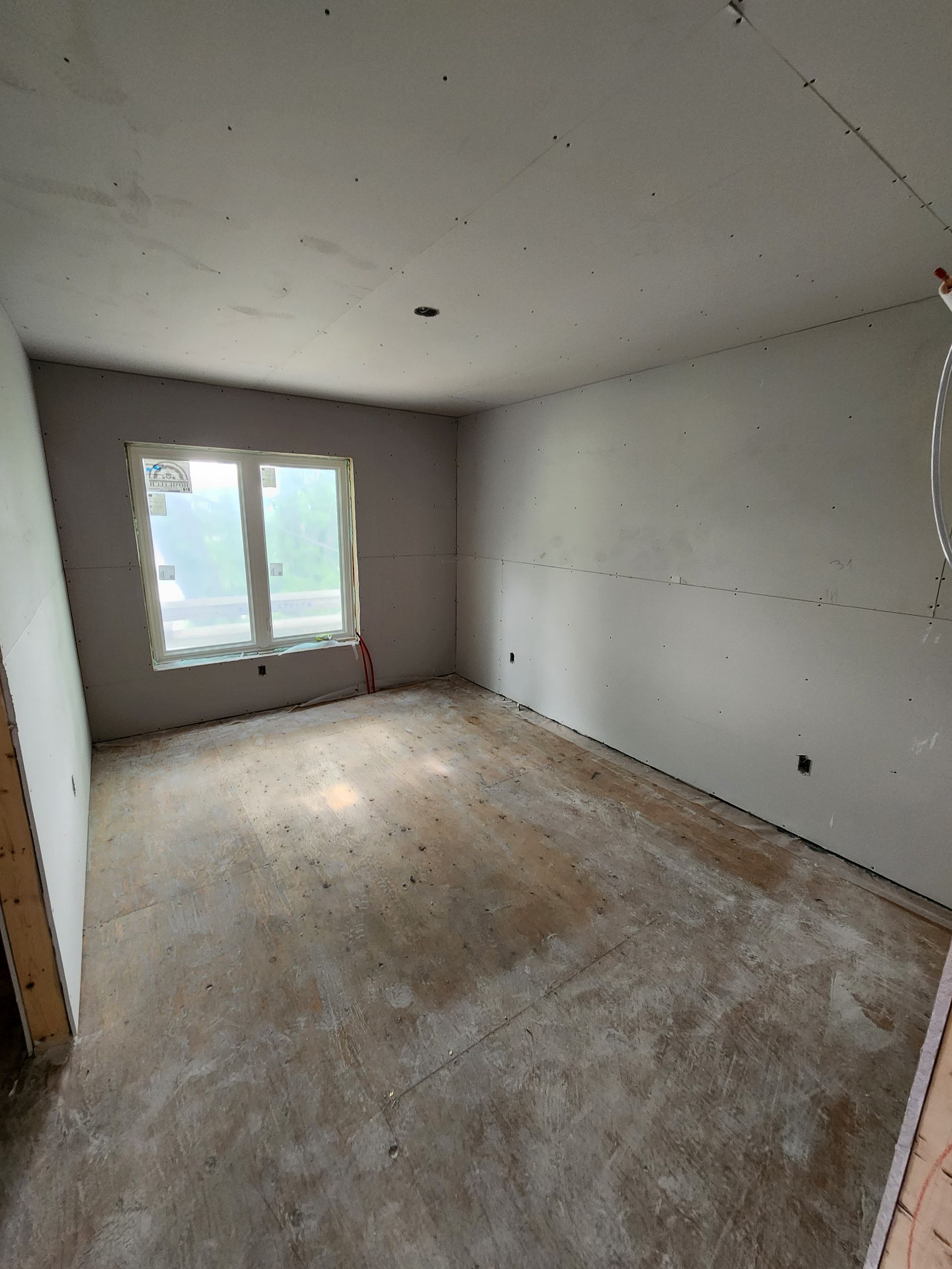 an empty room with a concrete floor and two windows .