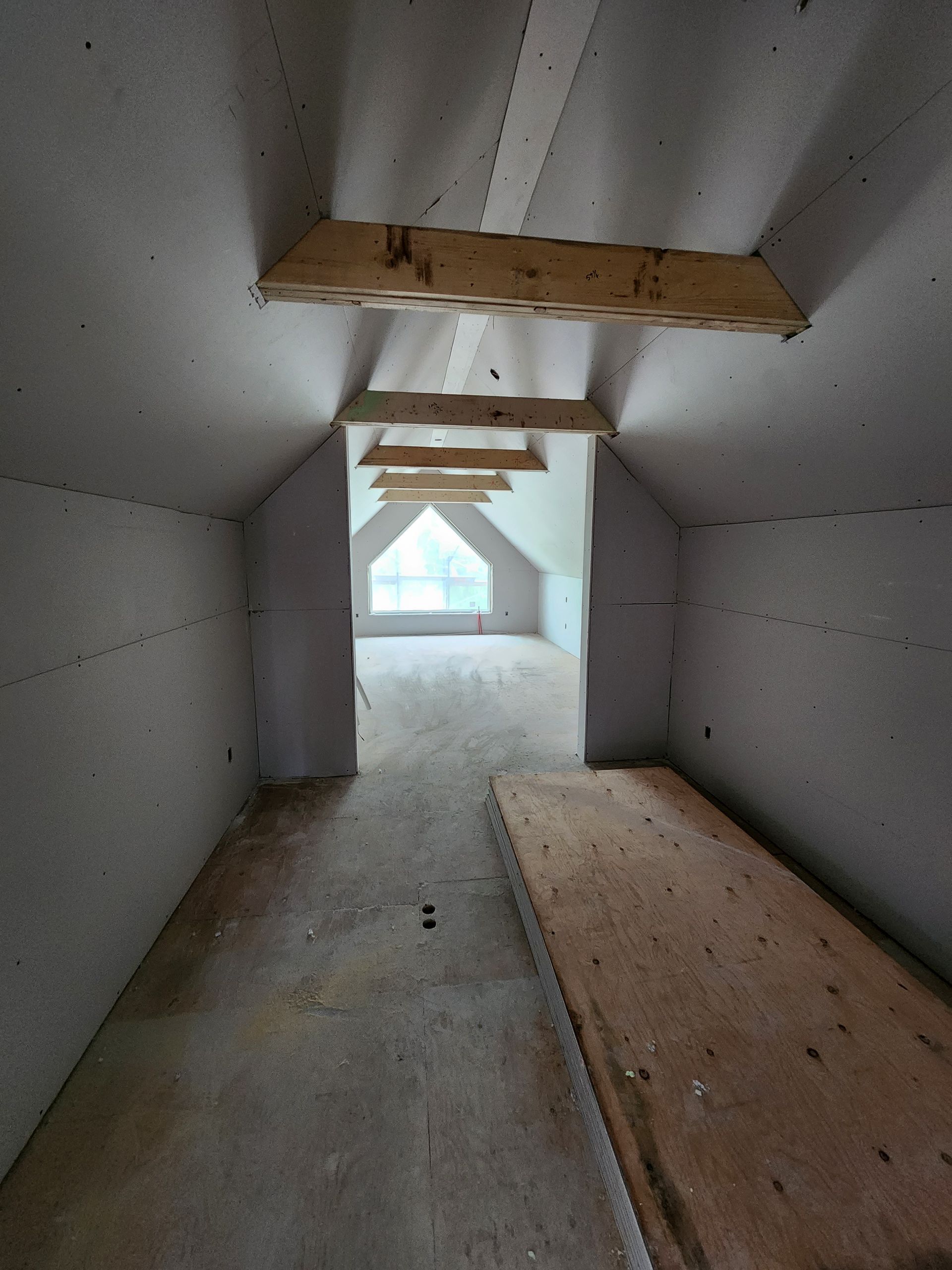 an empty attic with a window and wooden beams .