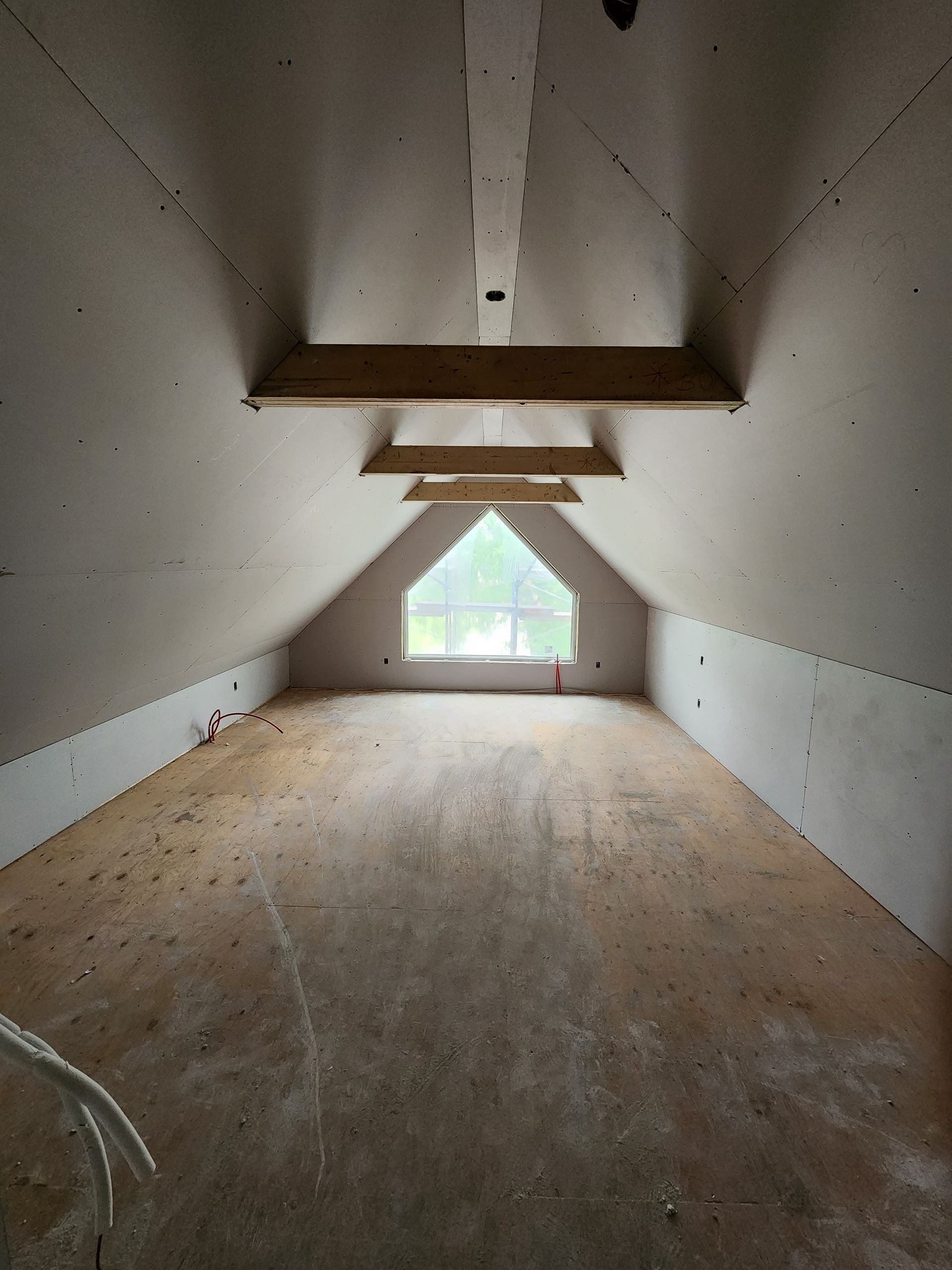 an empty attic with a window in the corner