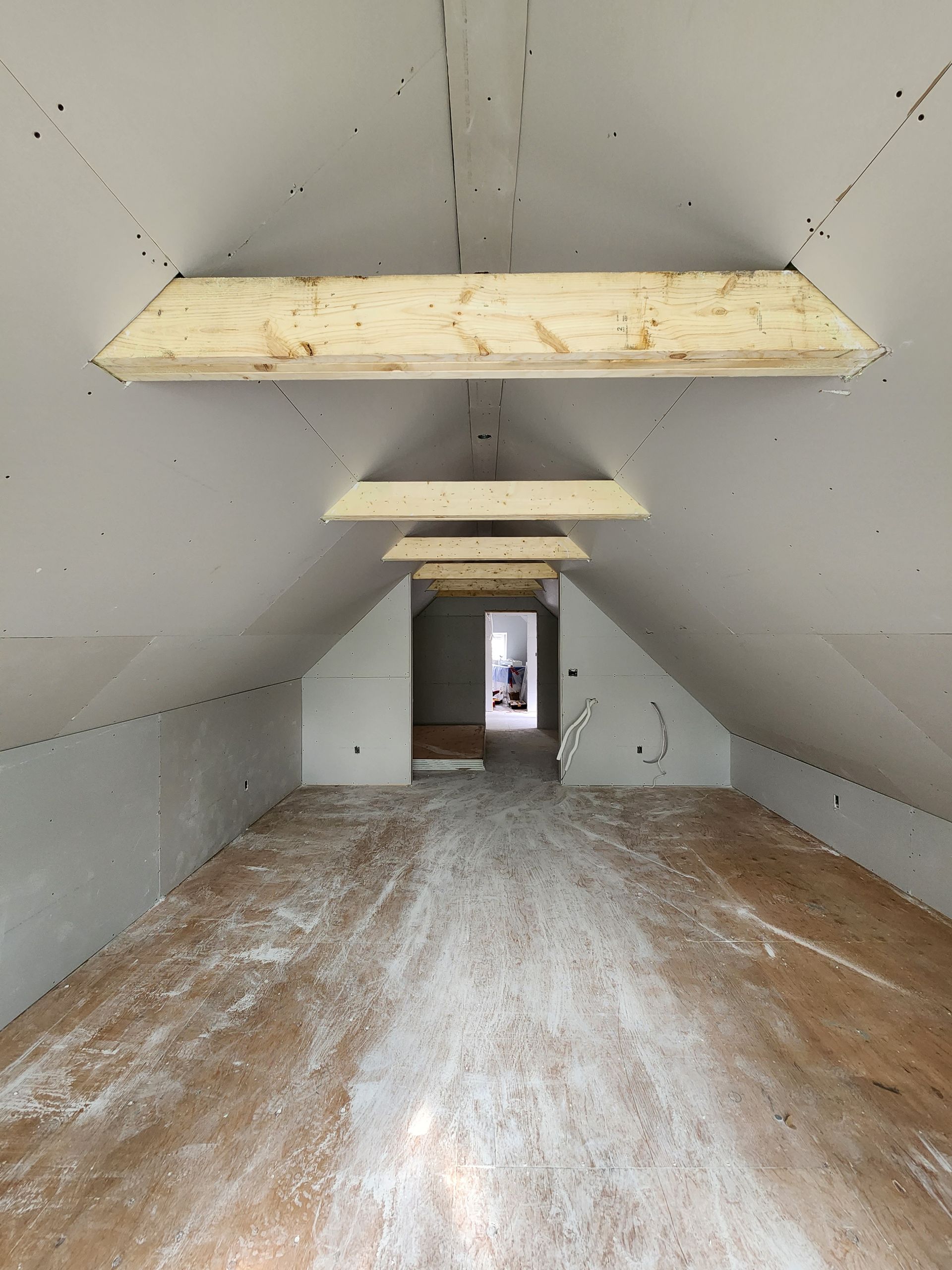 an empty attic with wooden beams hanging from the ceiling