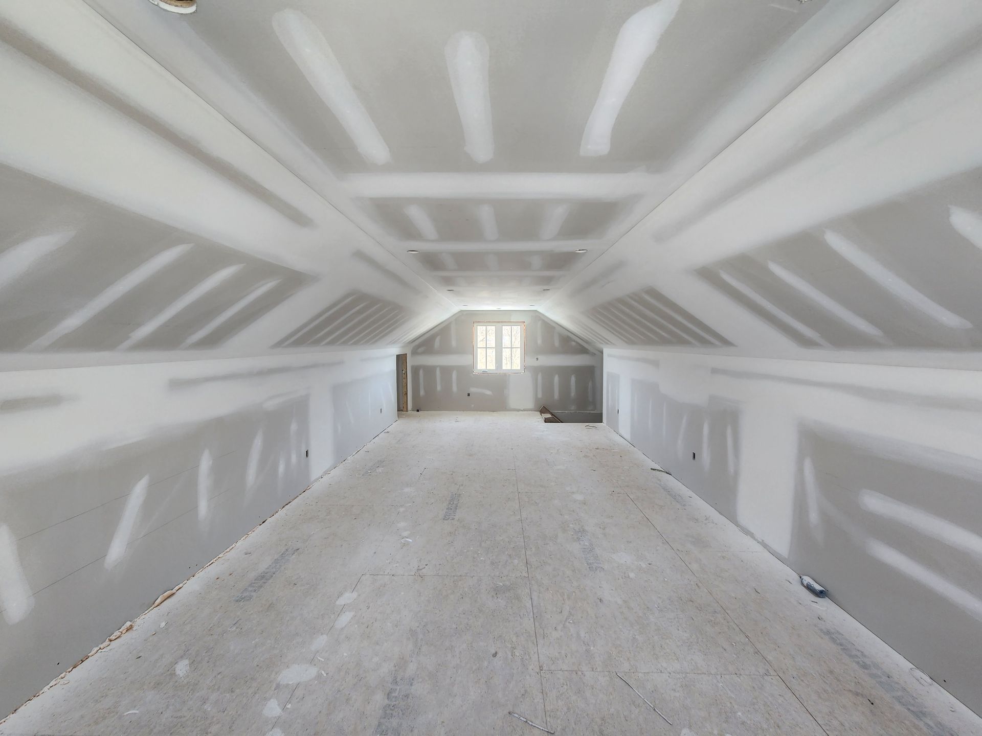 An empty attic with drywall on the walls and ceiling