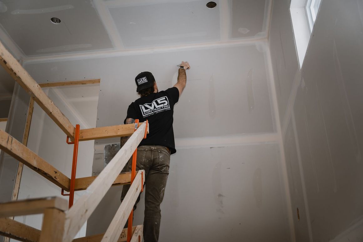 two construction workers are looking at a laptop on a construction site .