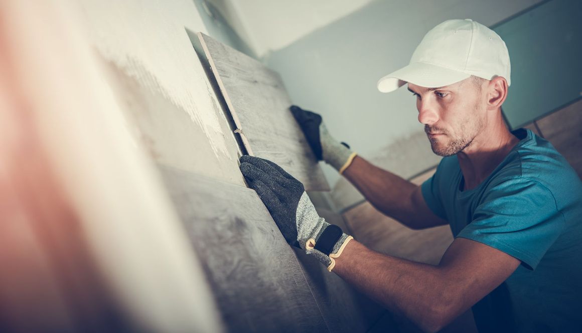 a man is laying tiles on a wall .