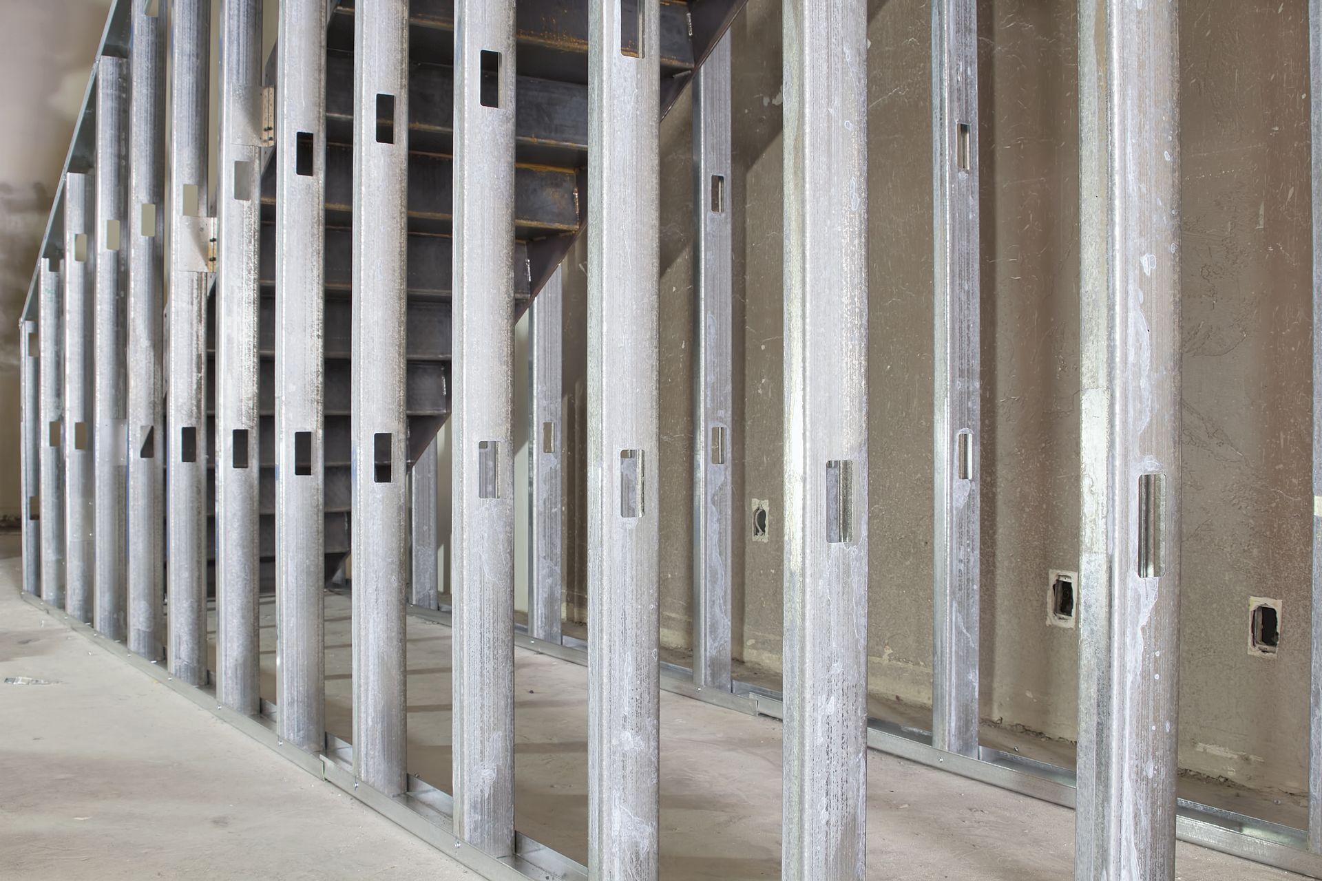 A row of metal frames in a room with a staircase in the background.