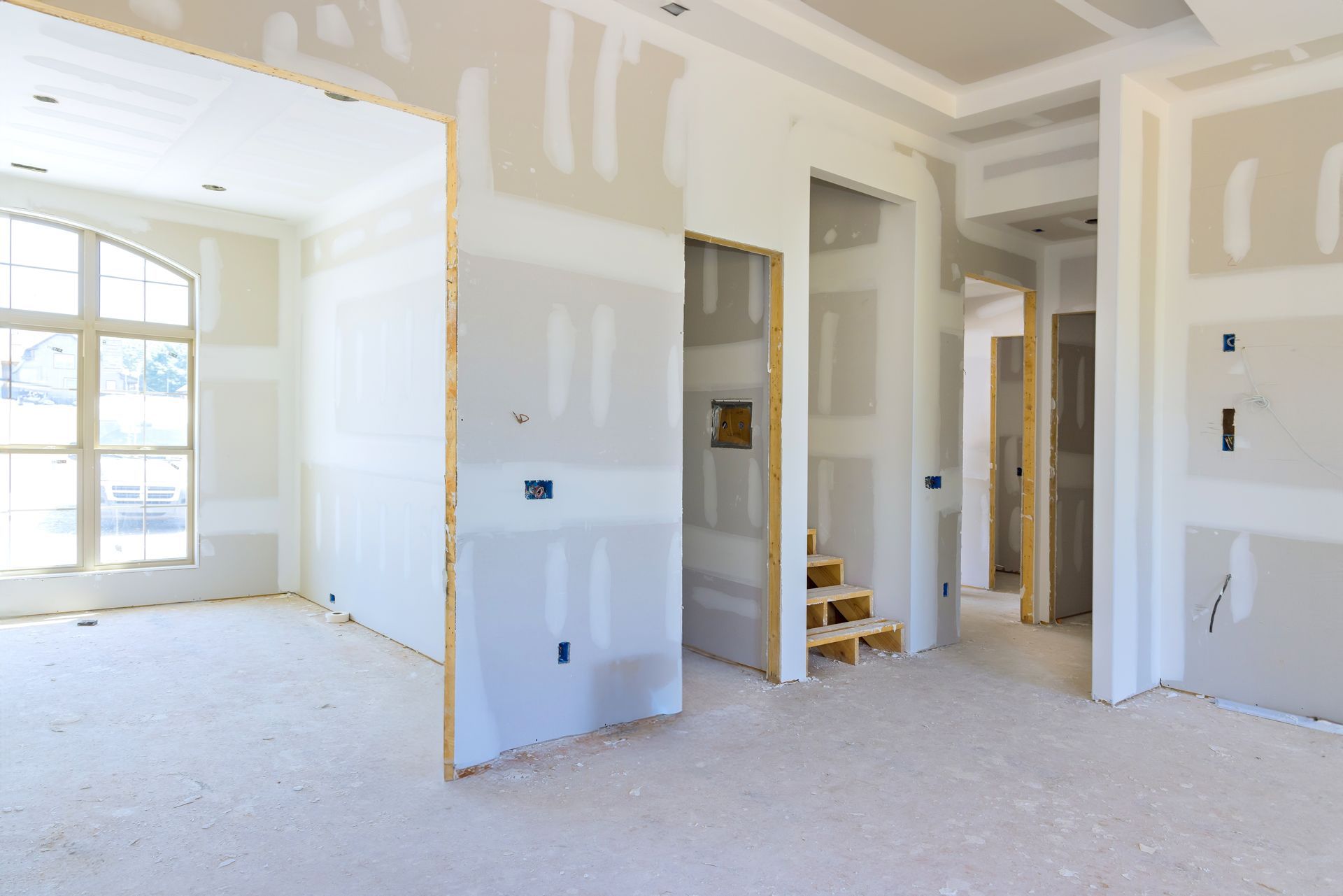 An empty room in a house under construction with drywall on the walls.