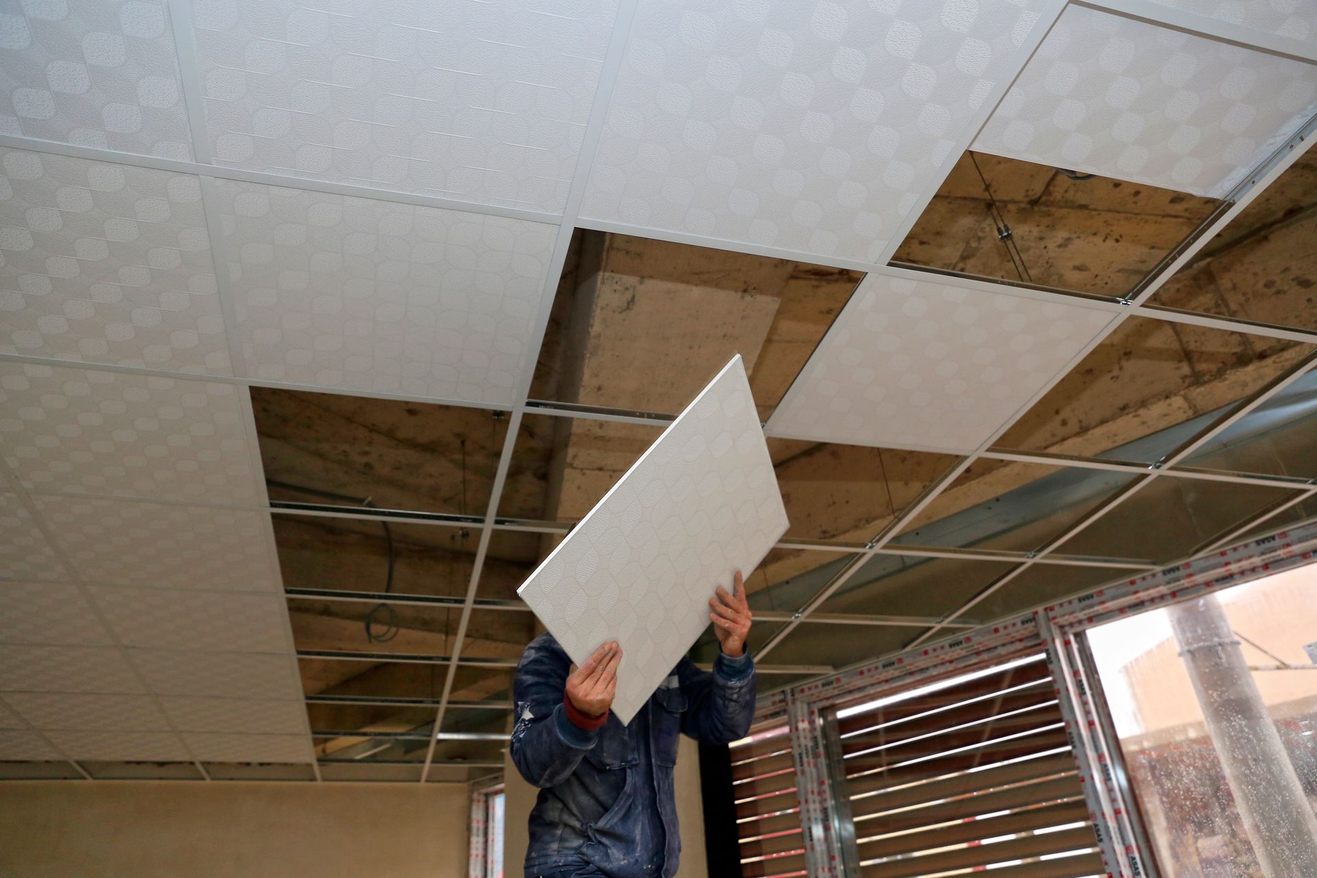 A man is holding a piece of white tile in his hands.